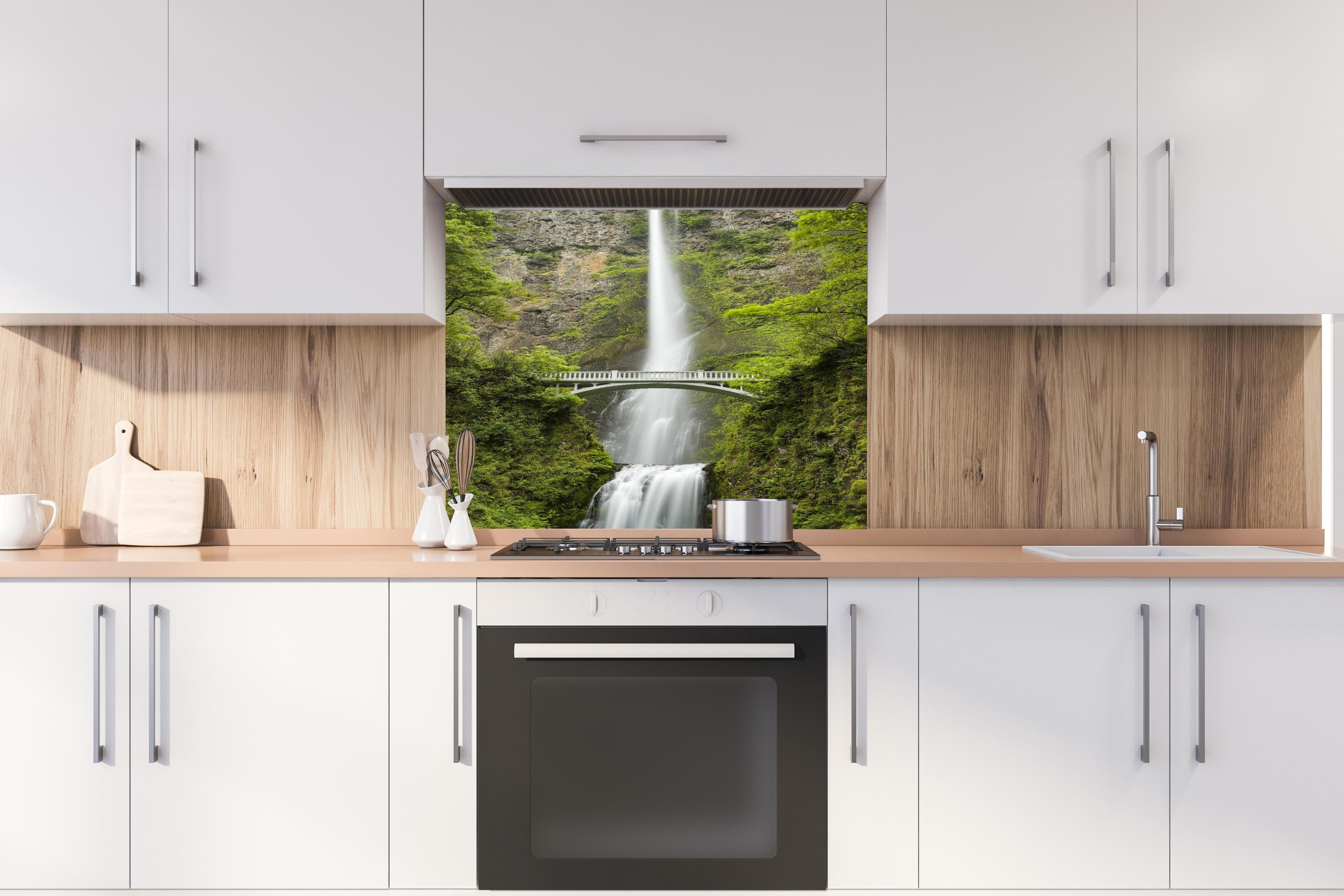 Spritzschutz - Brücke vor grünem Wasserfall Natur hinter einem Cerankochfeld zwischen Holz-Kochutensilien