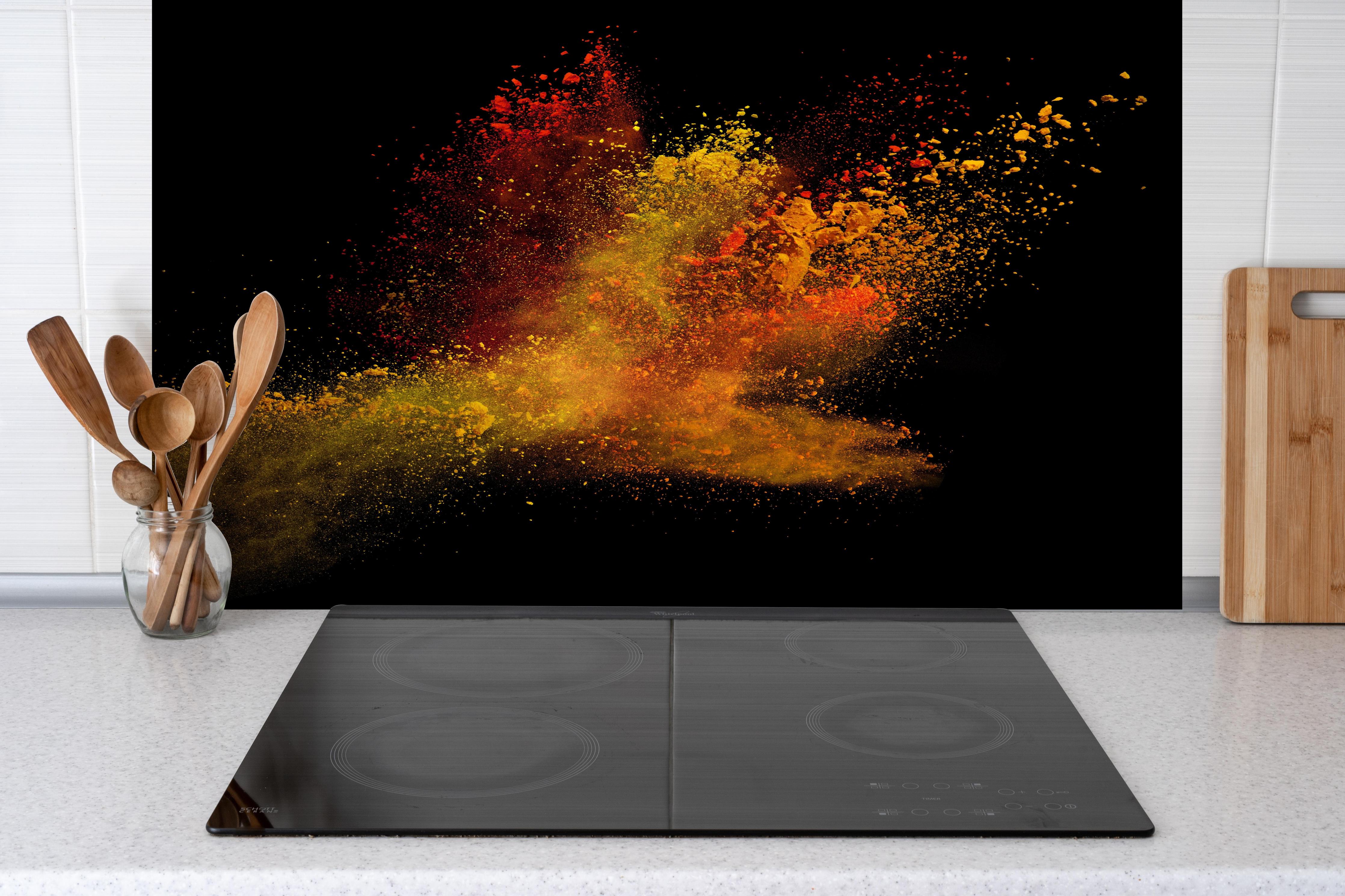 Spritzschutz - Bunte Farbexplosion hinter einem Cerankochfeld zwischen Holz-Kochutensilien
