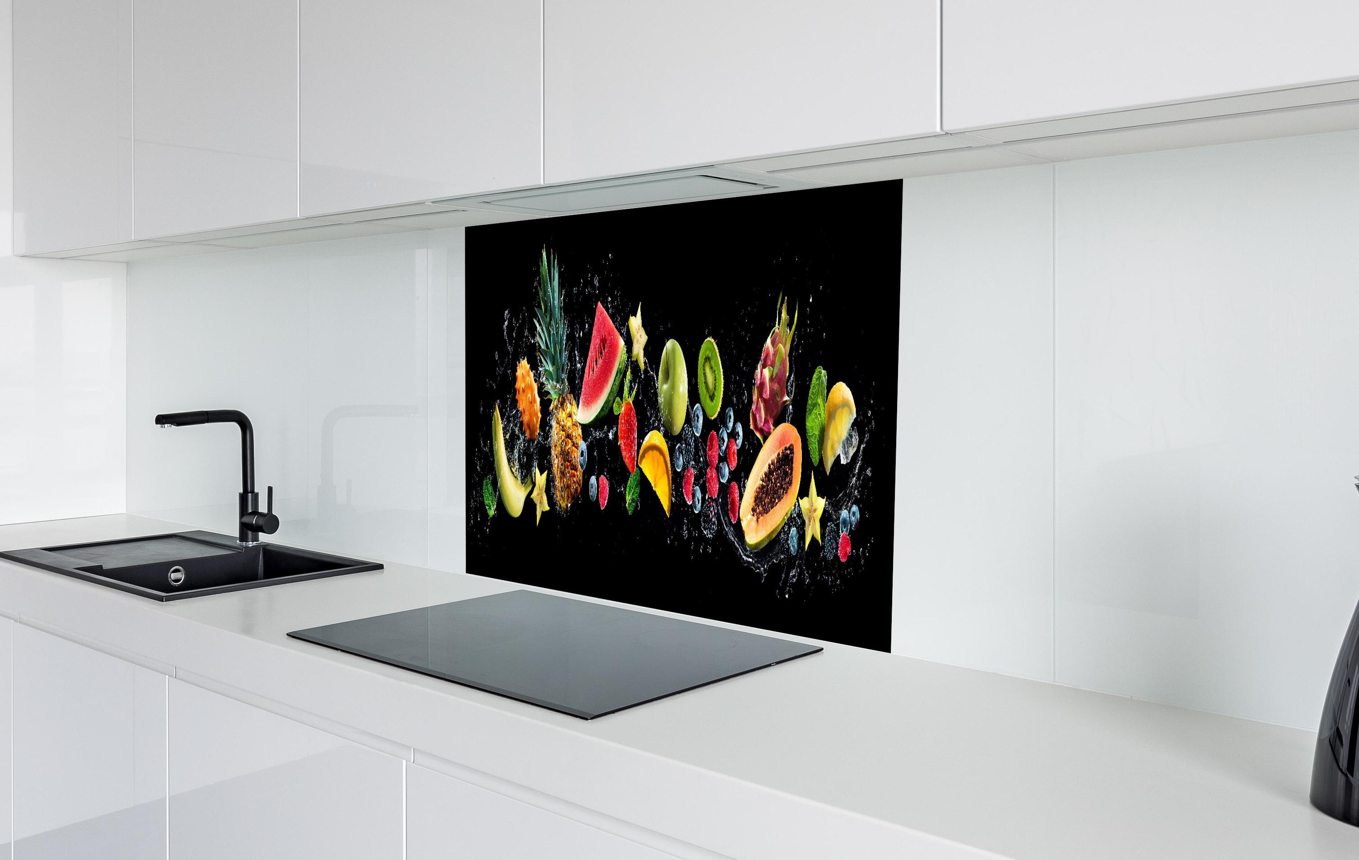 Spritzschutz - Bunte Früchte mit Wasserspritzern hinter einem Cerankochfeld zwischen Holz-Kochutensilien