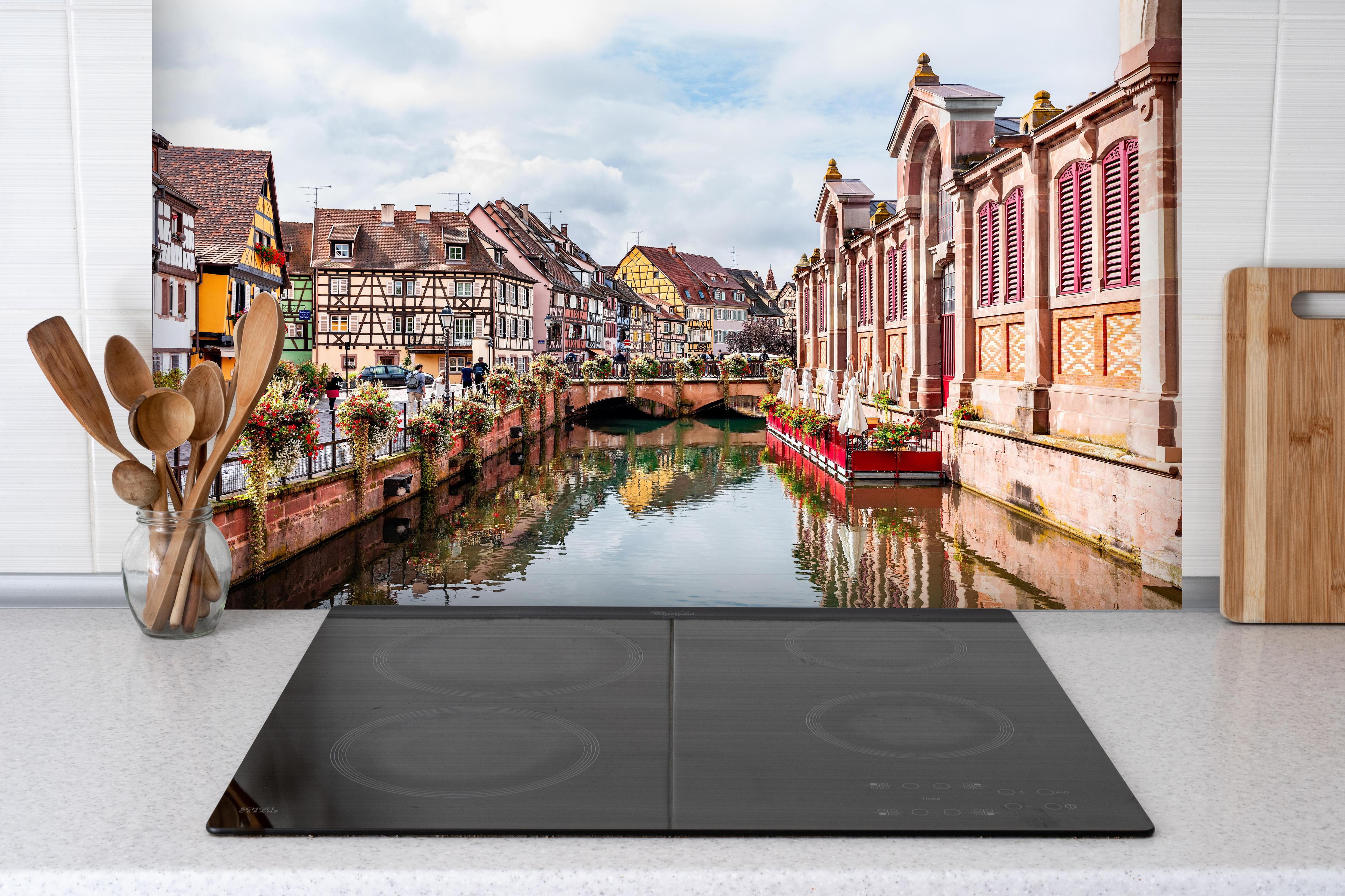 Spritzschutz - Bunte Häuser am Fluss in Colmar hinter einem Cerankochfeld zwischen Holz-Kochutensilien