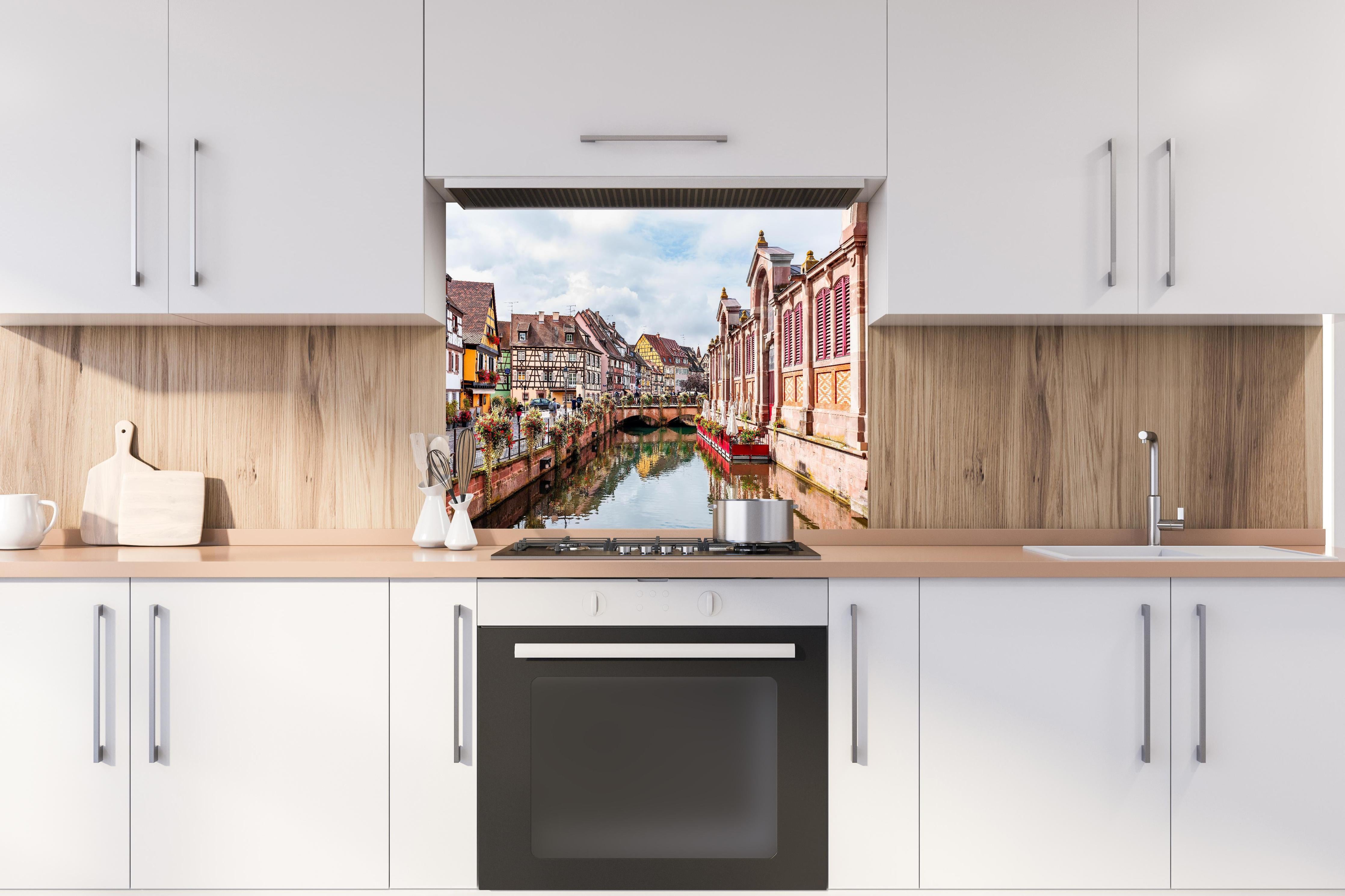 Spritzschutz - Bunte Häuser am Fluss in Colmar hinter einem Cerankochfeld zwischen Holz-Kochutensilien