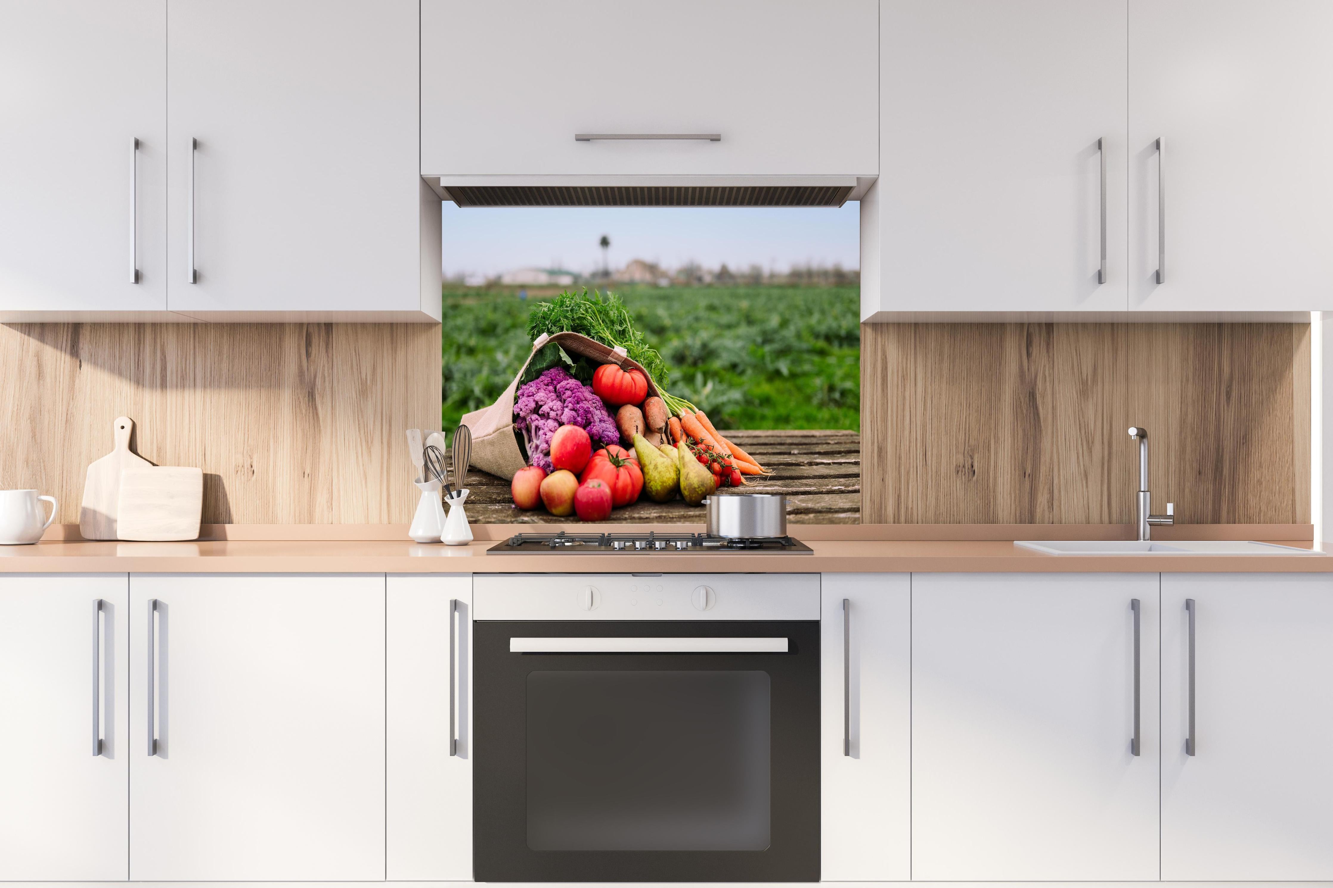 Spritzschutz - Bunte Vielfalt frischer Bio-Ernte hinter einem Cerankochfeld zwischen Holz-Kochutensilien