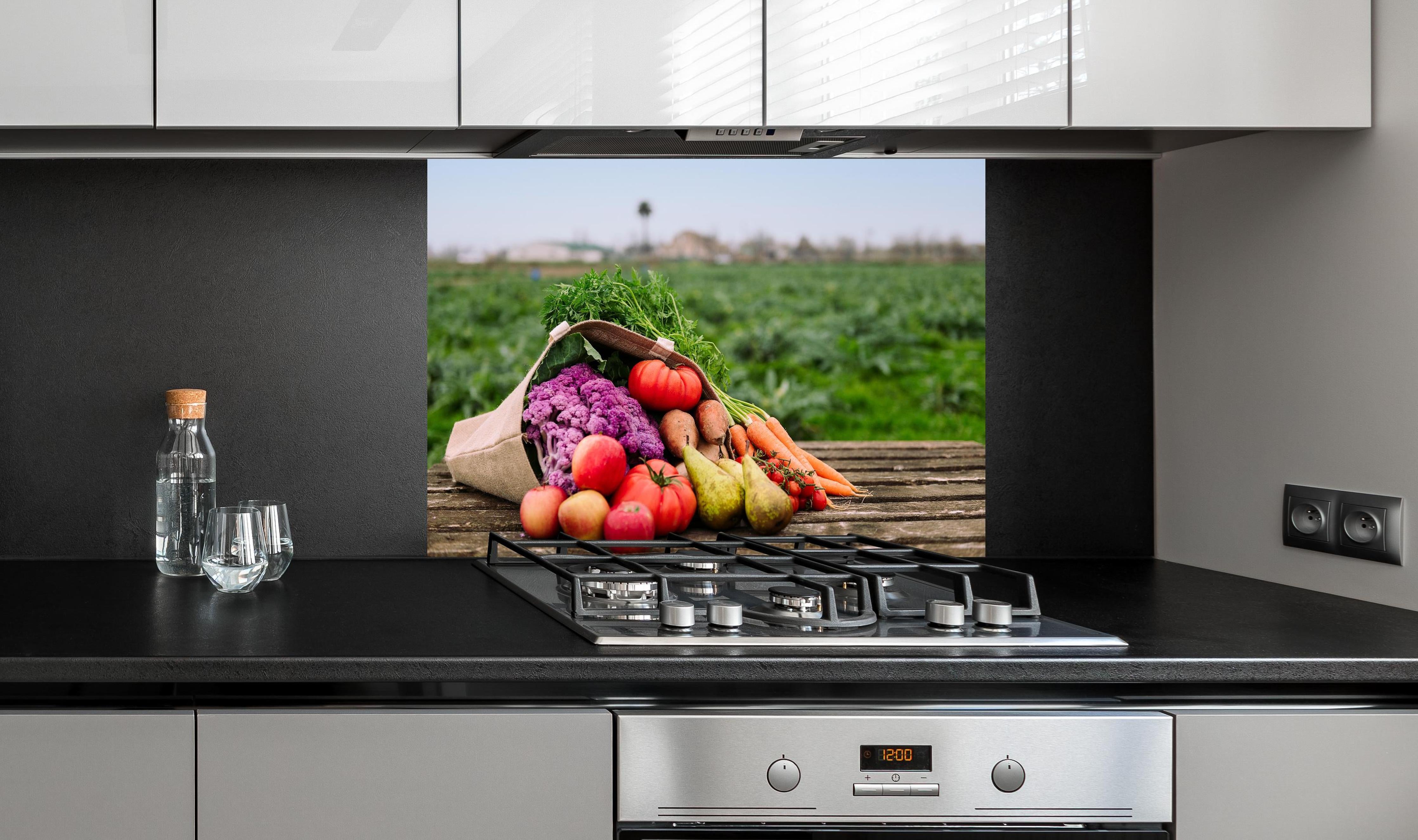 Spritzschutz - Bunte Vielfalt frischer Bio-Ernte hinter einem Cerankochfeld zwischen Holz-Kochutensilien