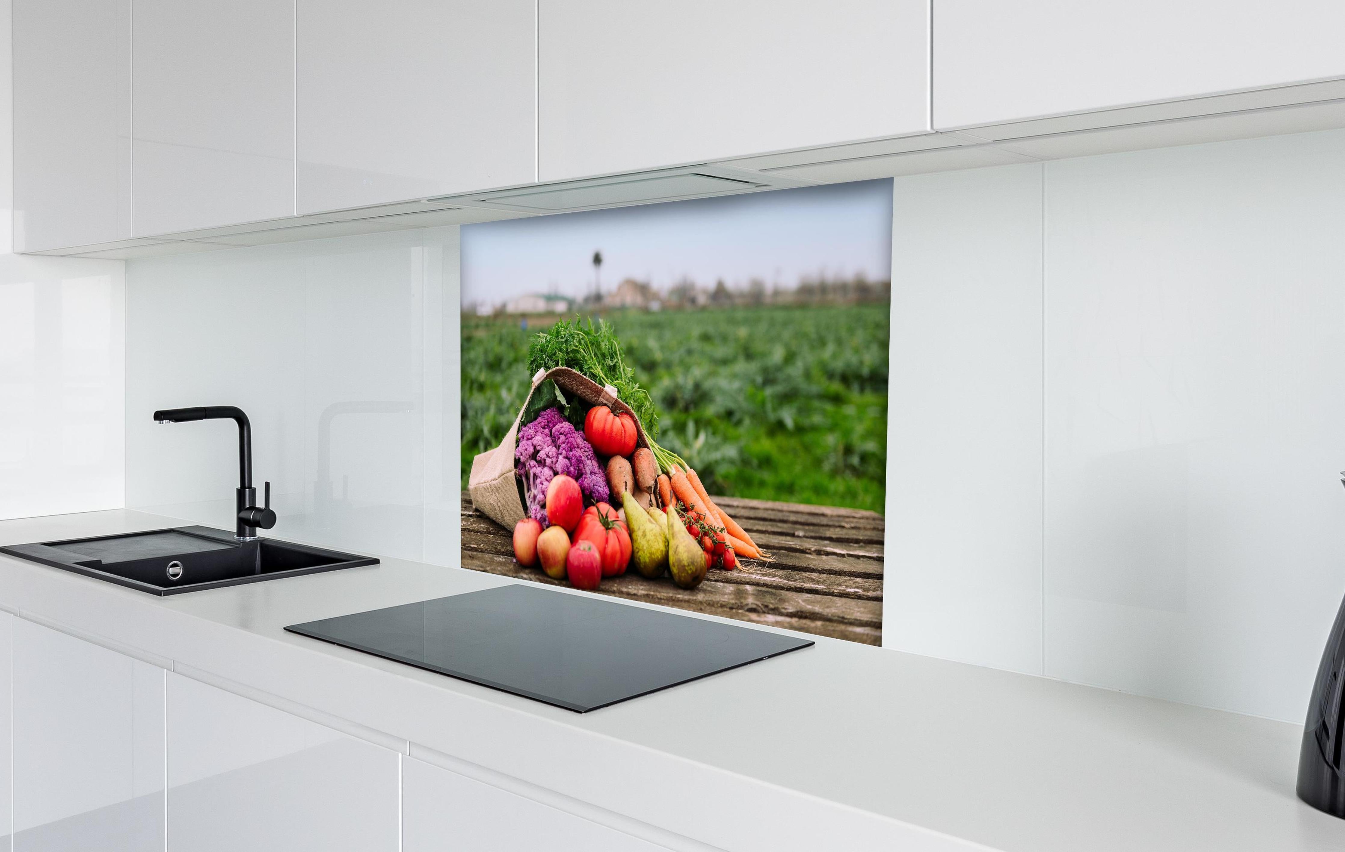 Spritzschutz - Bunte Vielfalt frischer Bio-Ernte hinter einem Cerankochfeld zwischen Holz-Kochutensilien