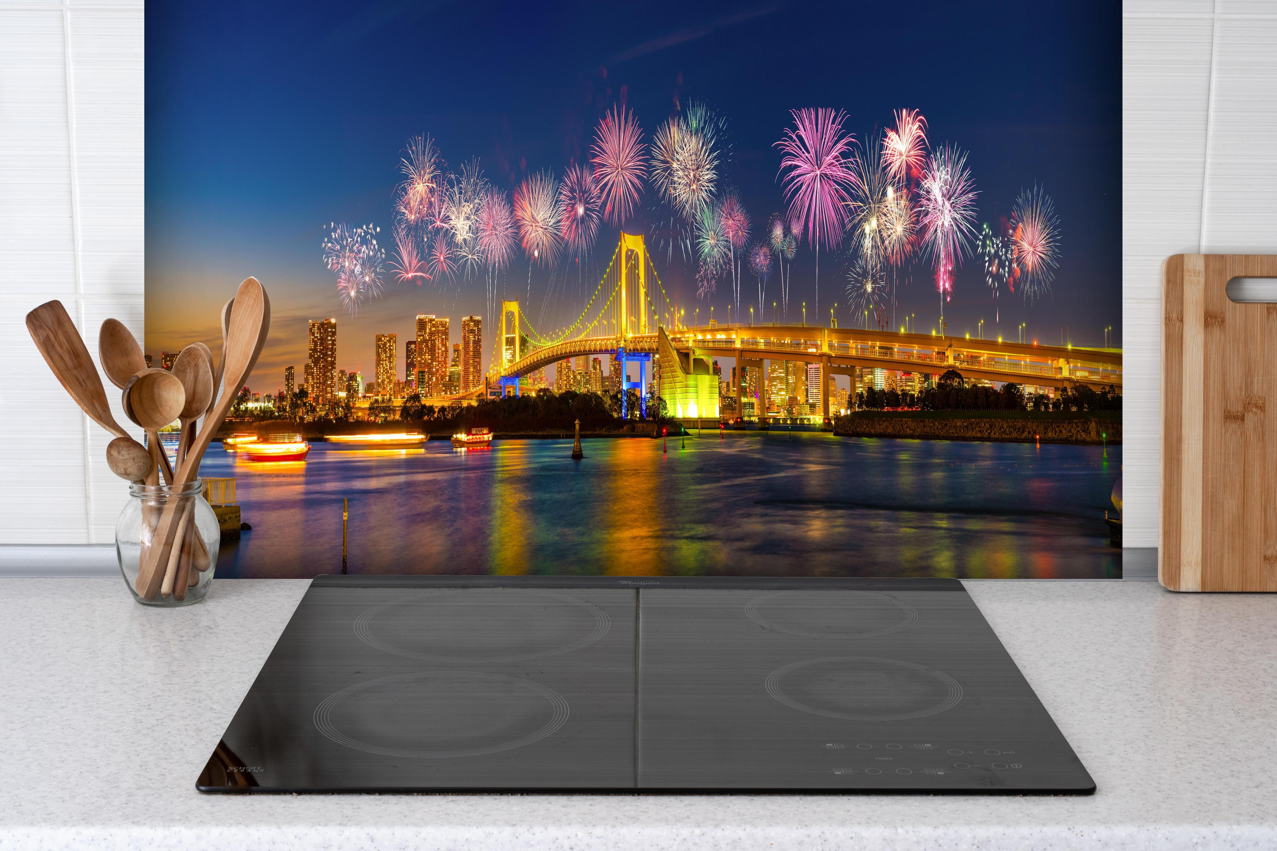 Spritzschutz - Buntes Feuerwerk Tokio Rainbow Bridge hinter einem Cerankochfeld zwischen Holz-Kochutensilien