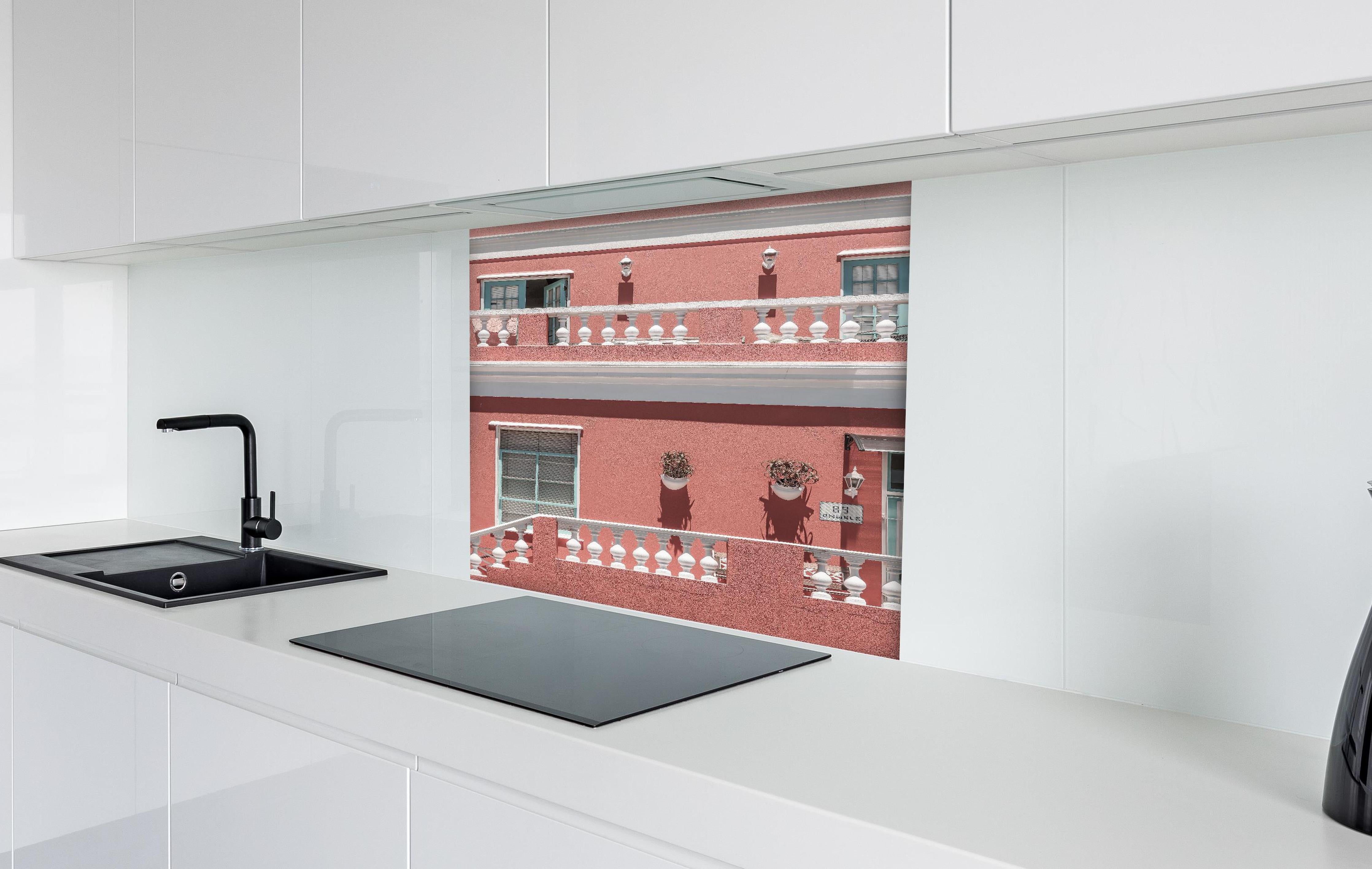 Spritzschutz - Buntes Gebäude mit pinker Fassade hinter einem Cerankochfeld zwischen Holz-Kochutensilien