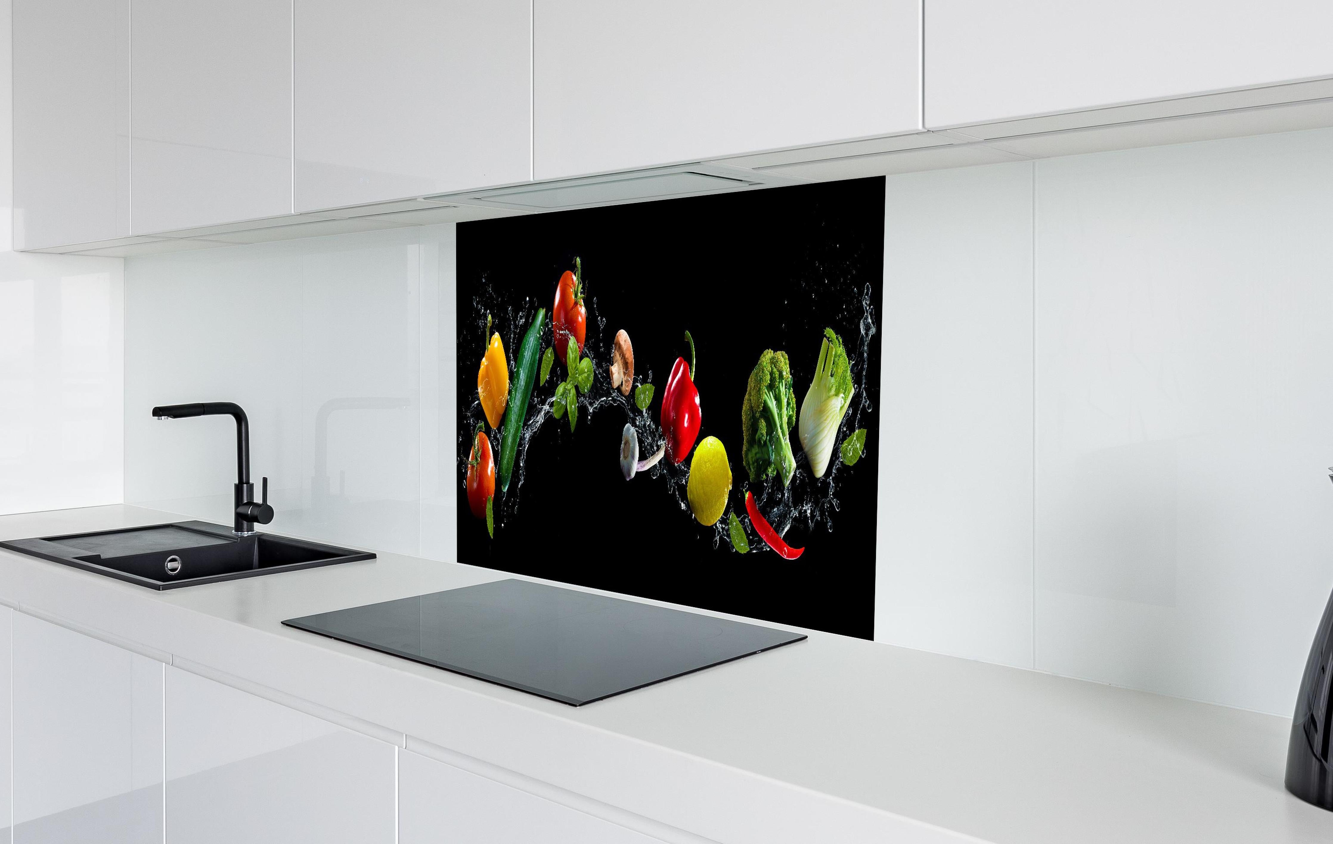 Spritzschutz - Buntes Spritzwasser-Gemüse auf Schwarz hinter einem Cerankochfeld zwischen Holz-Kochutensilien