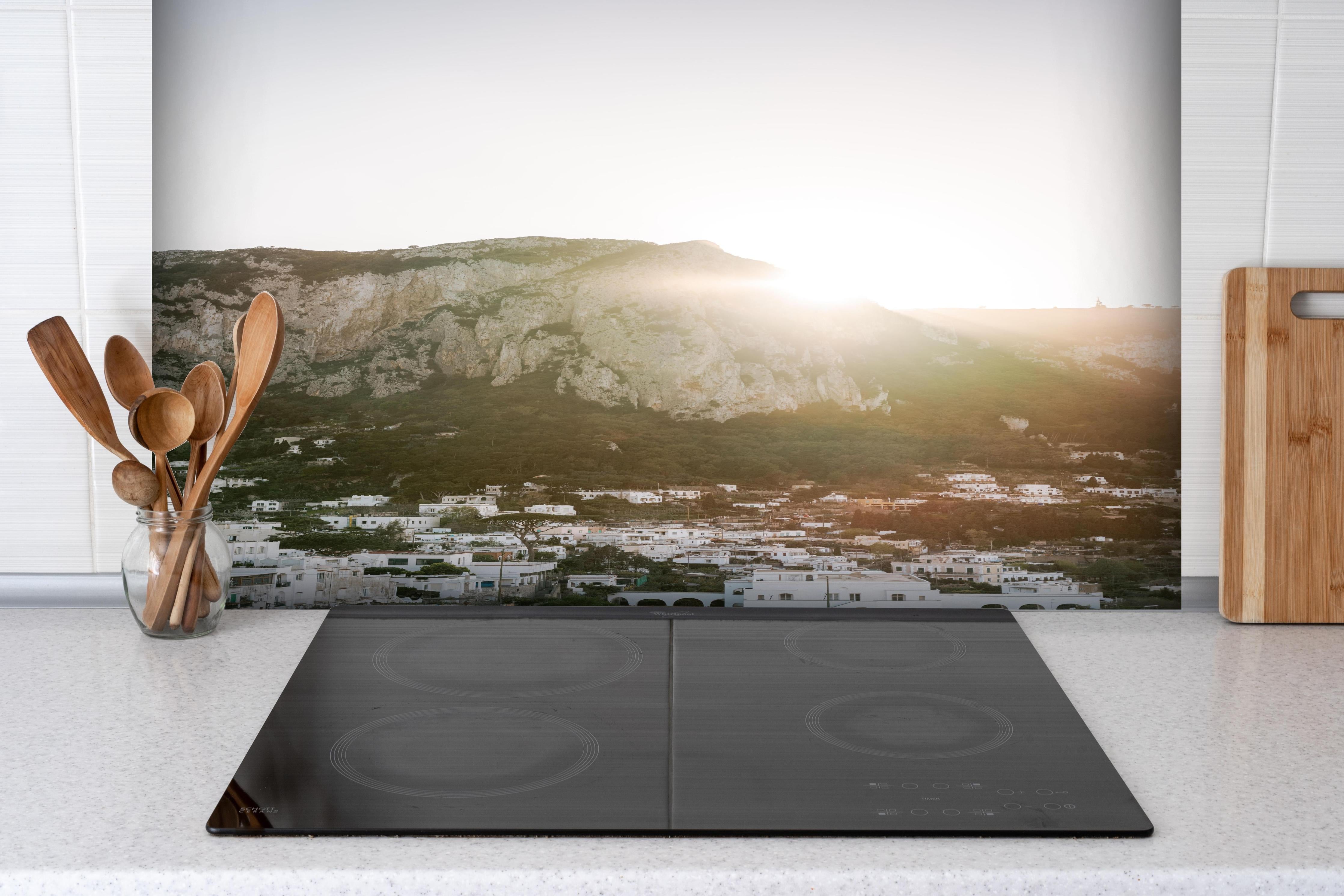 Spritzschutz - Capri Sonnenaufgang Berge Weiß-Grau hinter einem Cerankochfeld zwischen Holz-Kochutensilien