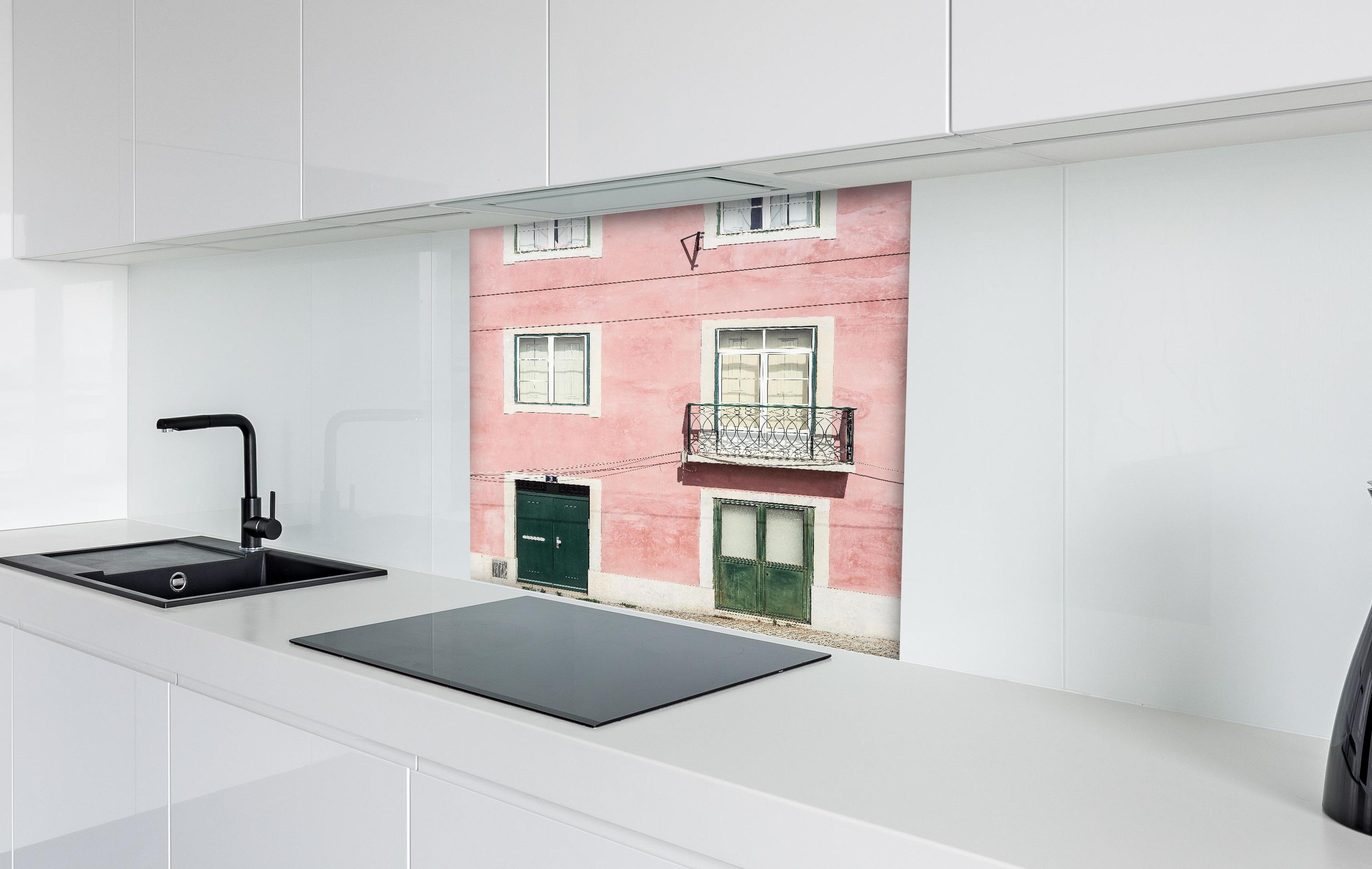 Spritzschutz - Charmante Pastellrosa Fassade mit Balkon hinter einem Cerankochfeld zwischen Holz-Kochutensilien