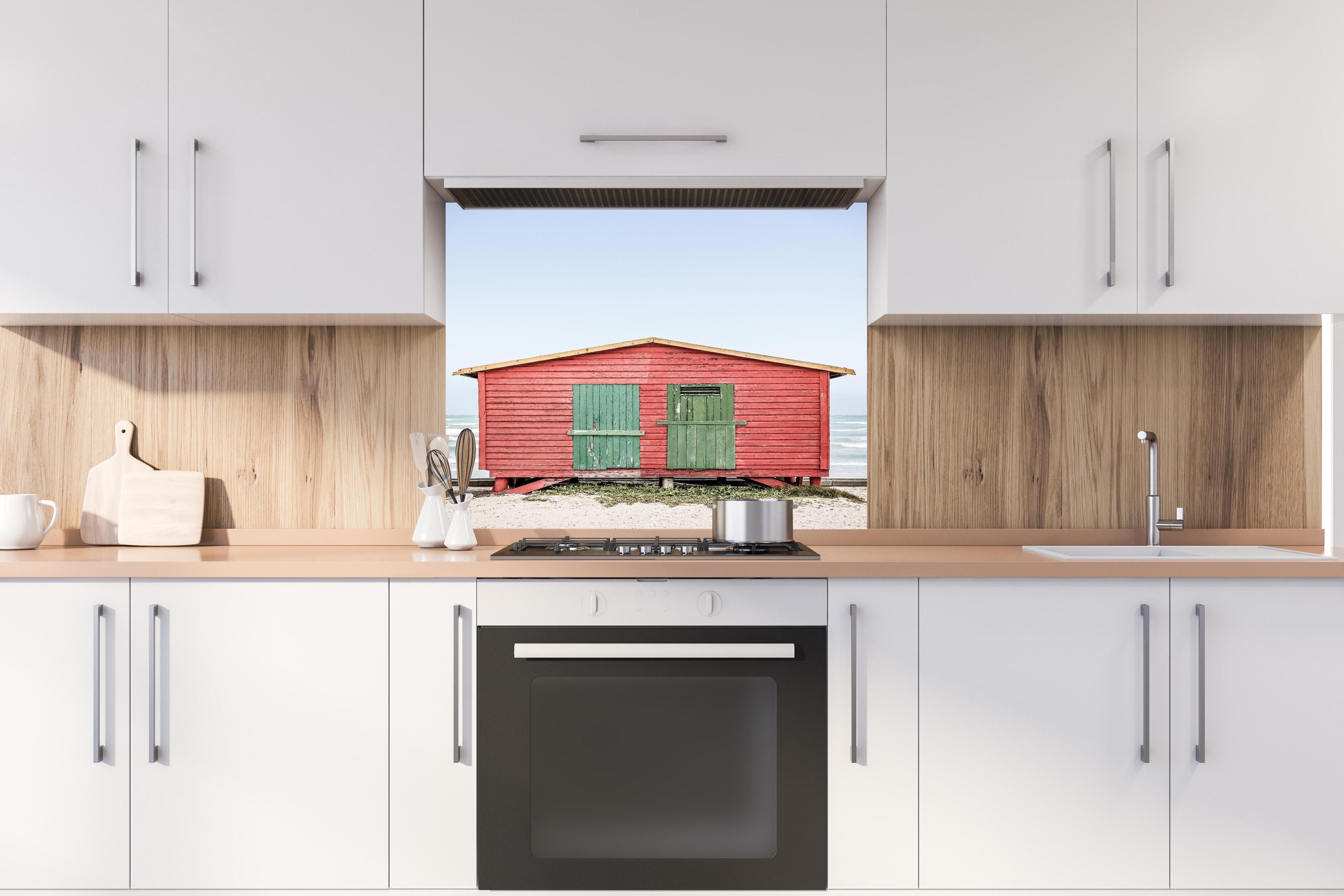 Spritzschutz - Charmante rote Strandhütte Küstenblick hinter einem Cerankochfeld zwischen Holz-Kochutensilien