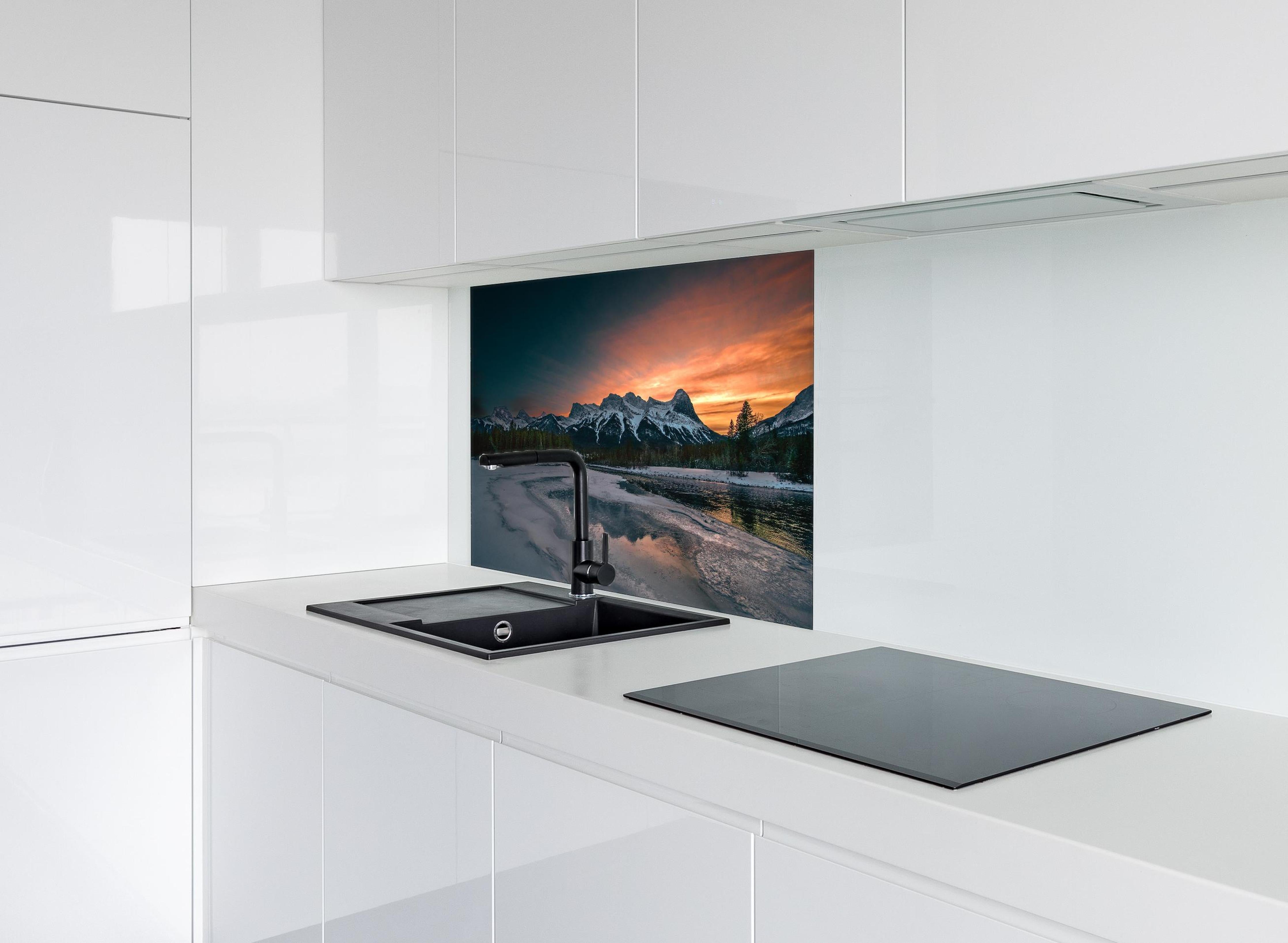 Spritzschutz - Dämmerung über schneebedeckten Bergspitzen hinter einem Cerankochfeld zwischen Holz-Kochutensilien