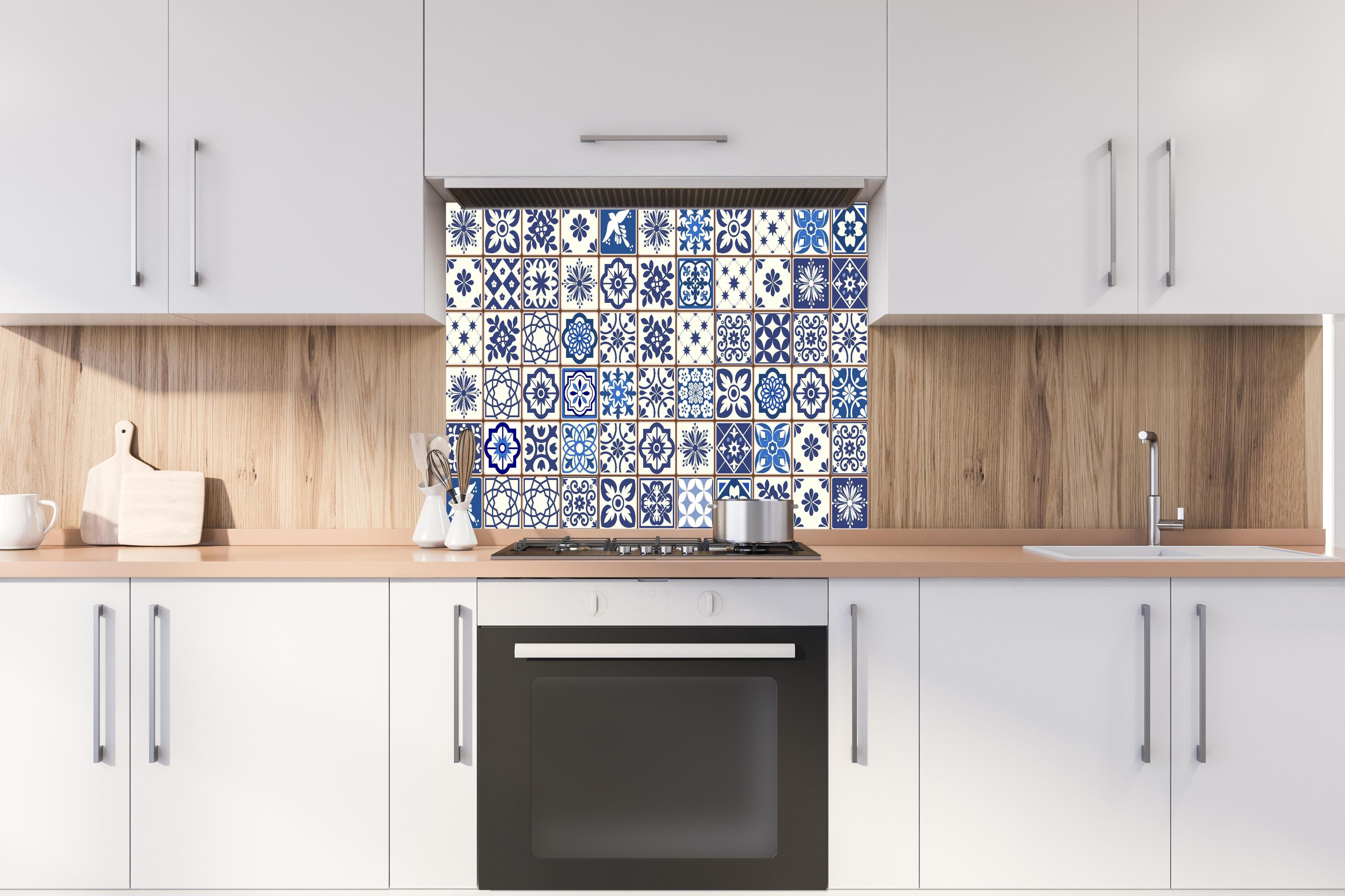 Spritzschutz - Dekorative blaue Keramik Kacheln mit Mustern hinter einem Cerankochfeld zwischen Holz-Kochutensilien