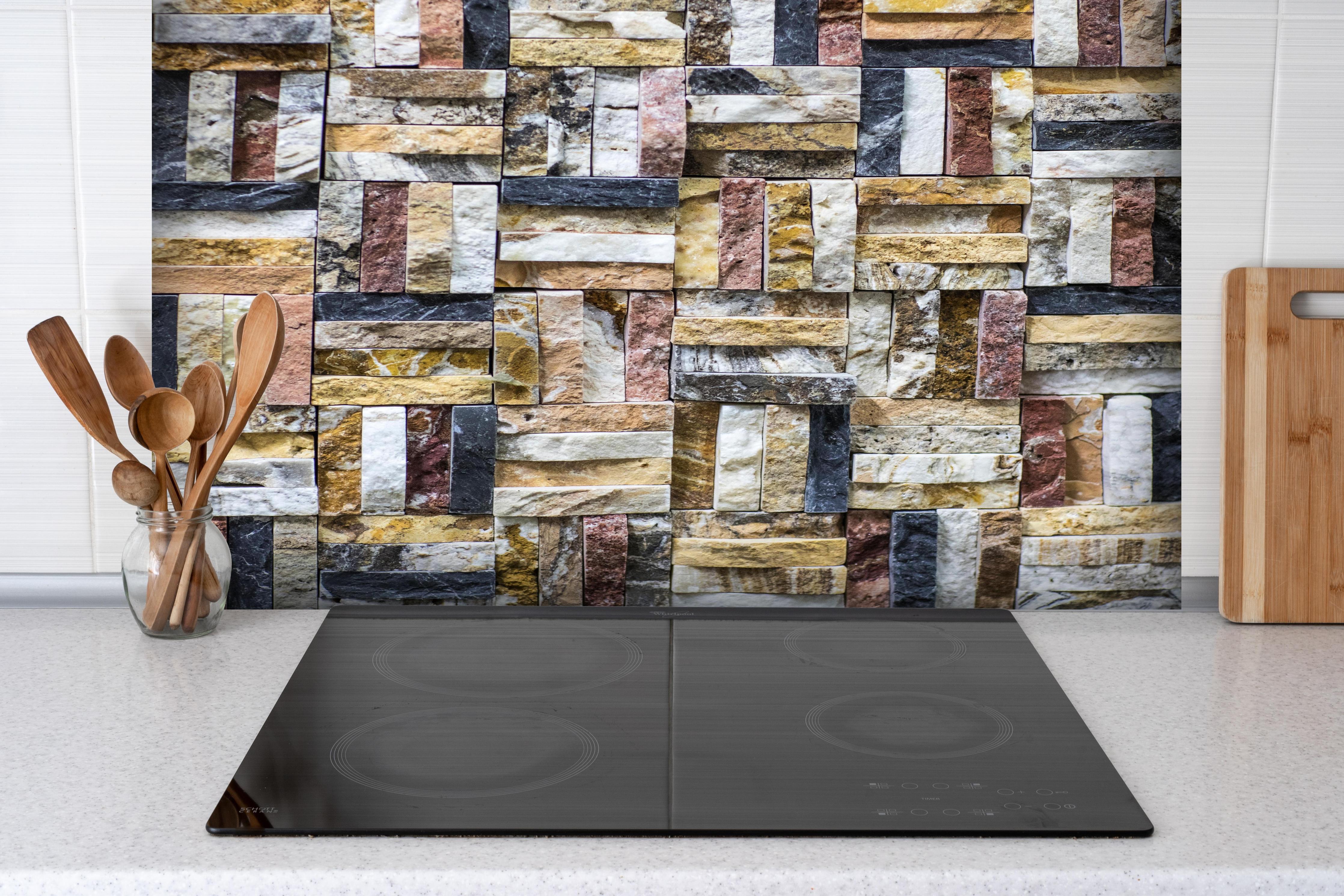 Spritzschutz - Dekoratives Wand Mosaik aus Naturstein hinter einem Cerankochfeld zwischen Holz-Kochutensilien