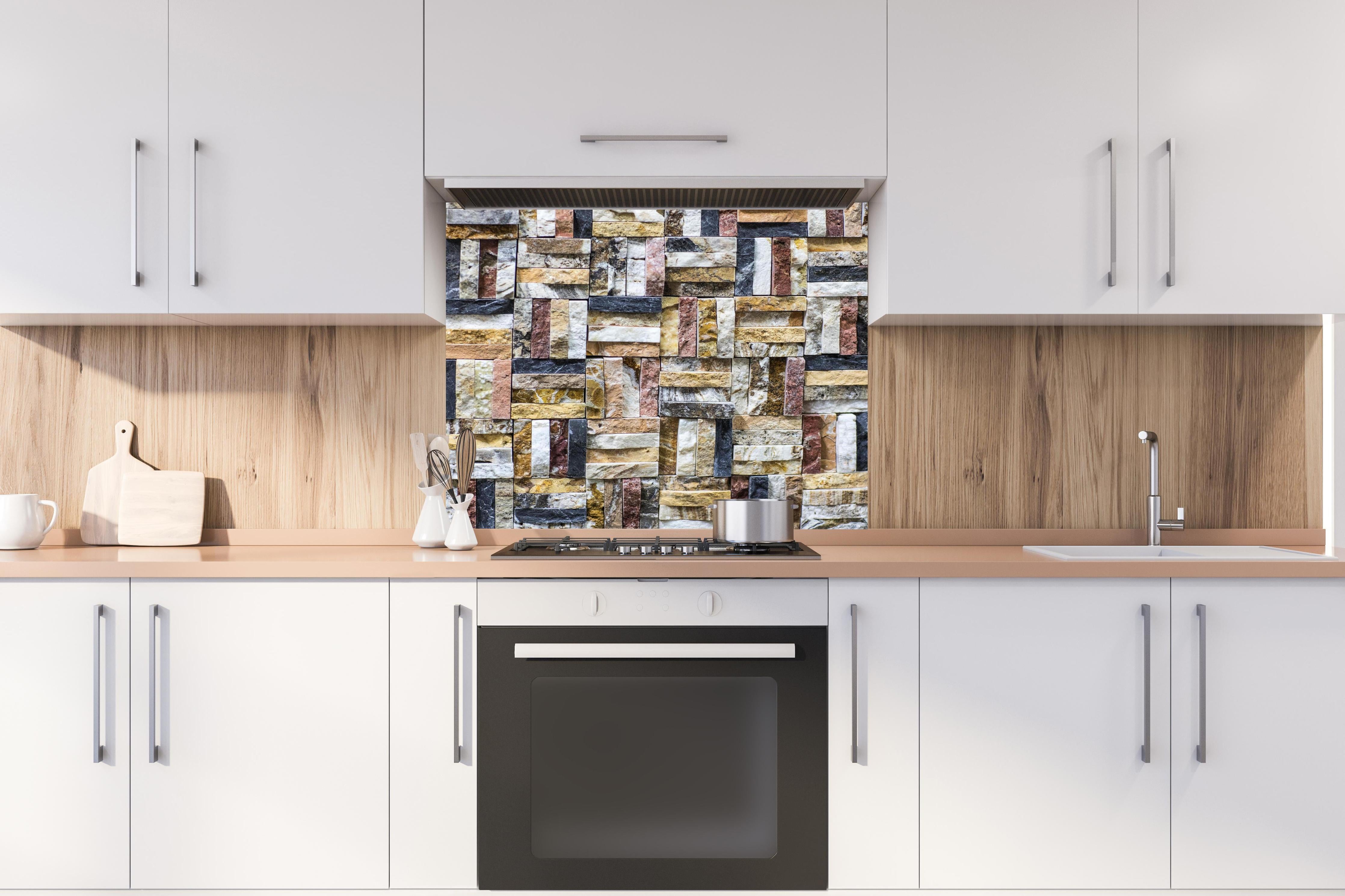 Spritzschutz - Dekoratives Wand Mosaik aus Naturstein hinter einem Cerankochfeld zwischen Holz-Kochutensilien