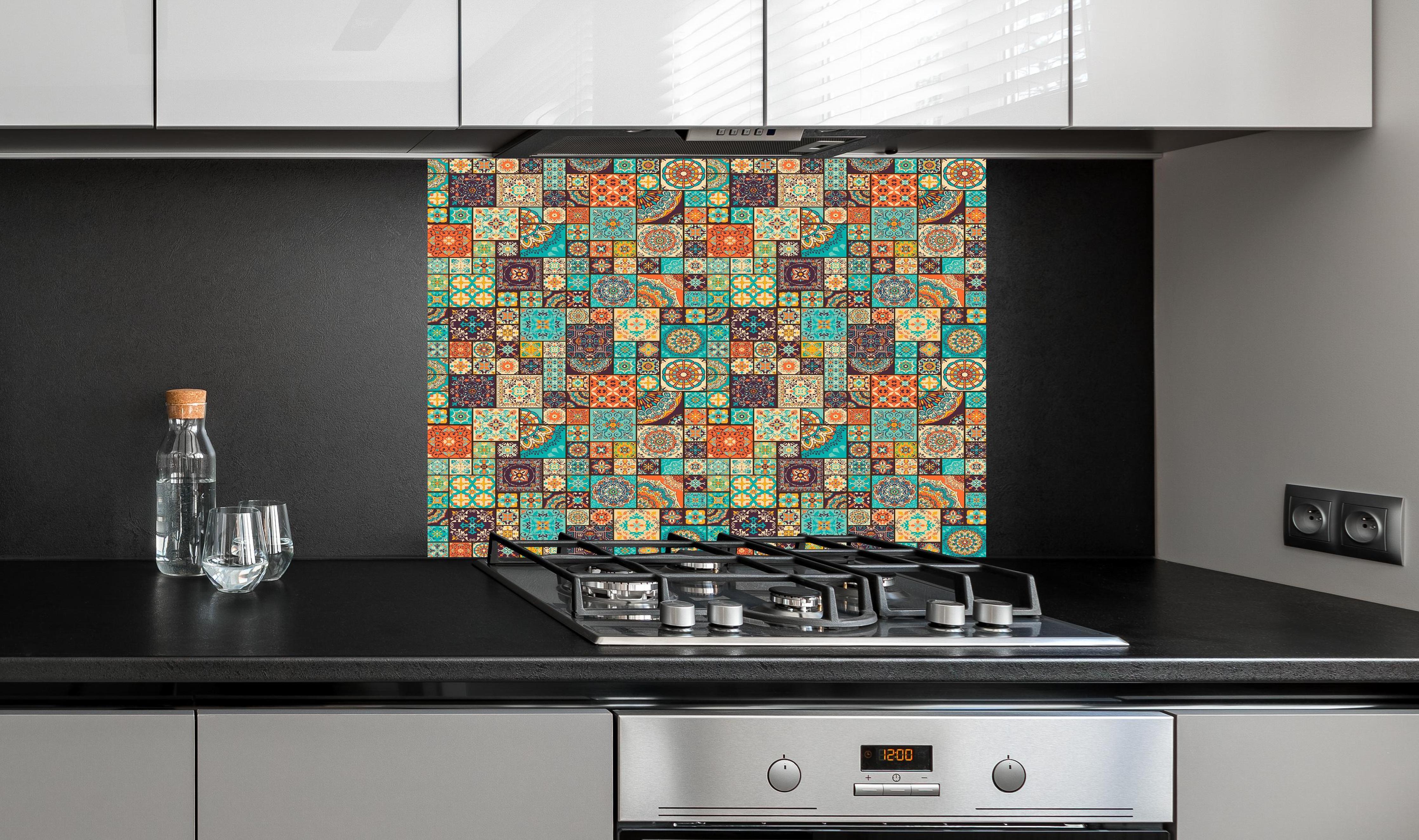 Spritzschutz - Dekoratives buntes Patchwork-Fliesen-Design hinter einem Cerankochfeld zwischen Holz-Kochutensilien