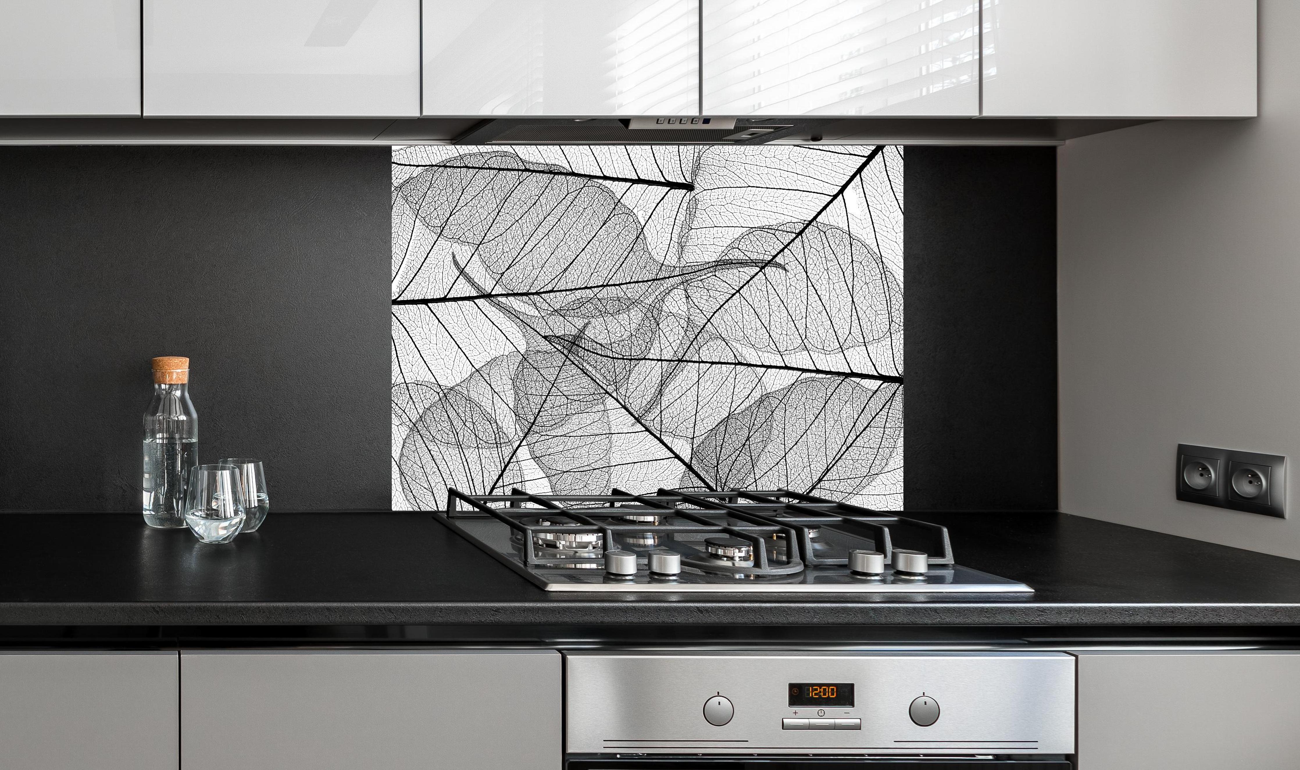 Spritzschutz - Detaillierte Schwarz-Weiße Laubtextur hinter einem Cerankochfeld zwischen Holz-Kochutensilien