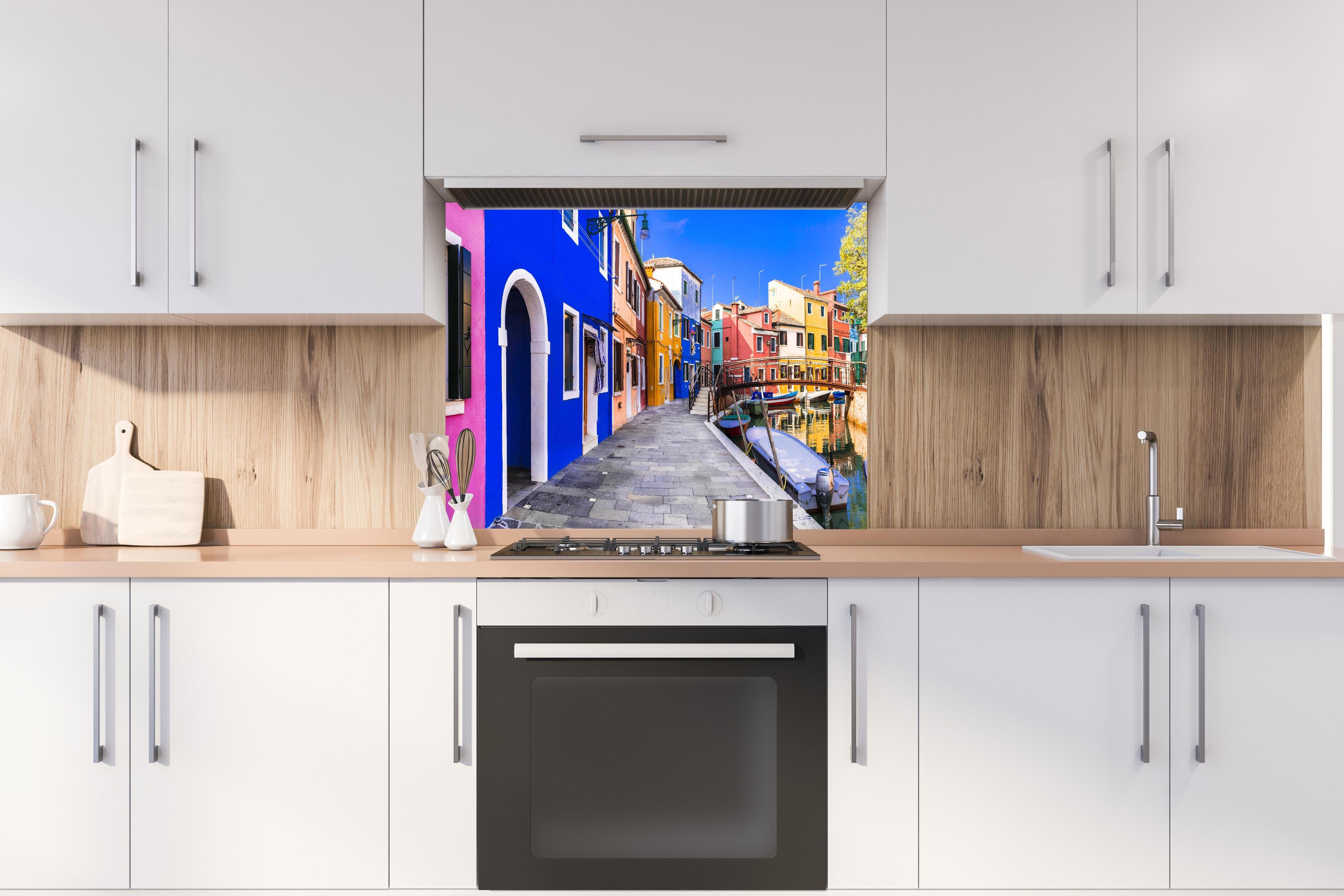 Spritzschutz - Die farbenfrohe Insel Burano hinter einem Cerankochfeld zwischen Holz-Kochutensilien