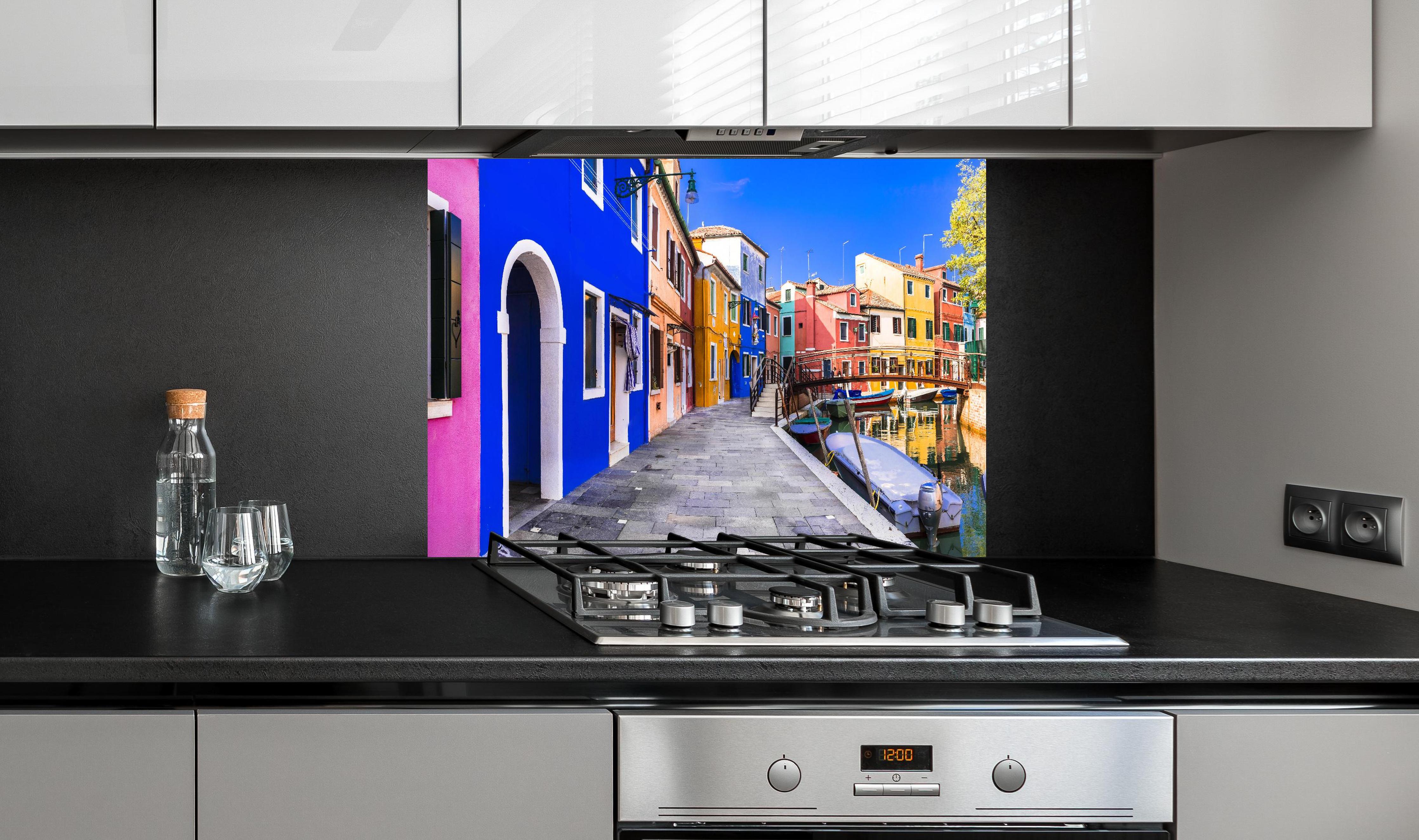 Spritzschutz - Die farbenfrohe Insel Burano hinter einem Cerankochfeld zwischen Holz-Kochutensilien