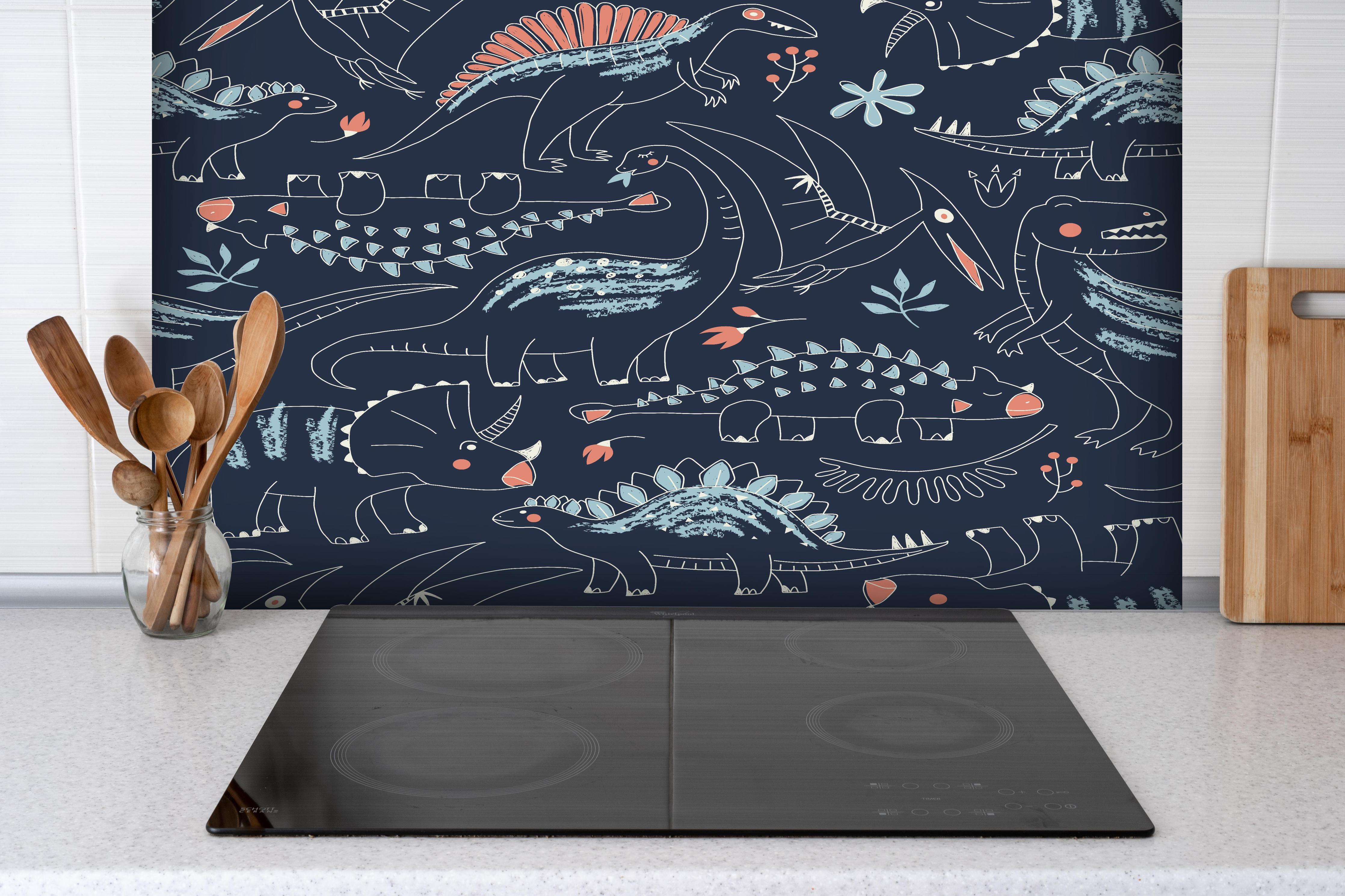 Spritzschutz - Dunkelblaues Dino-Muster für Kinder hinter einem Cerankochfeld zwischen Holz-Kochutensilien