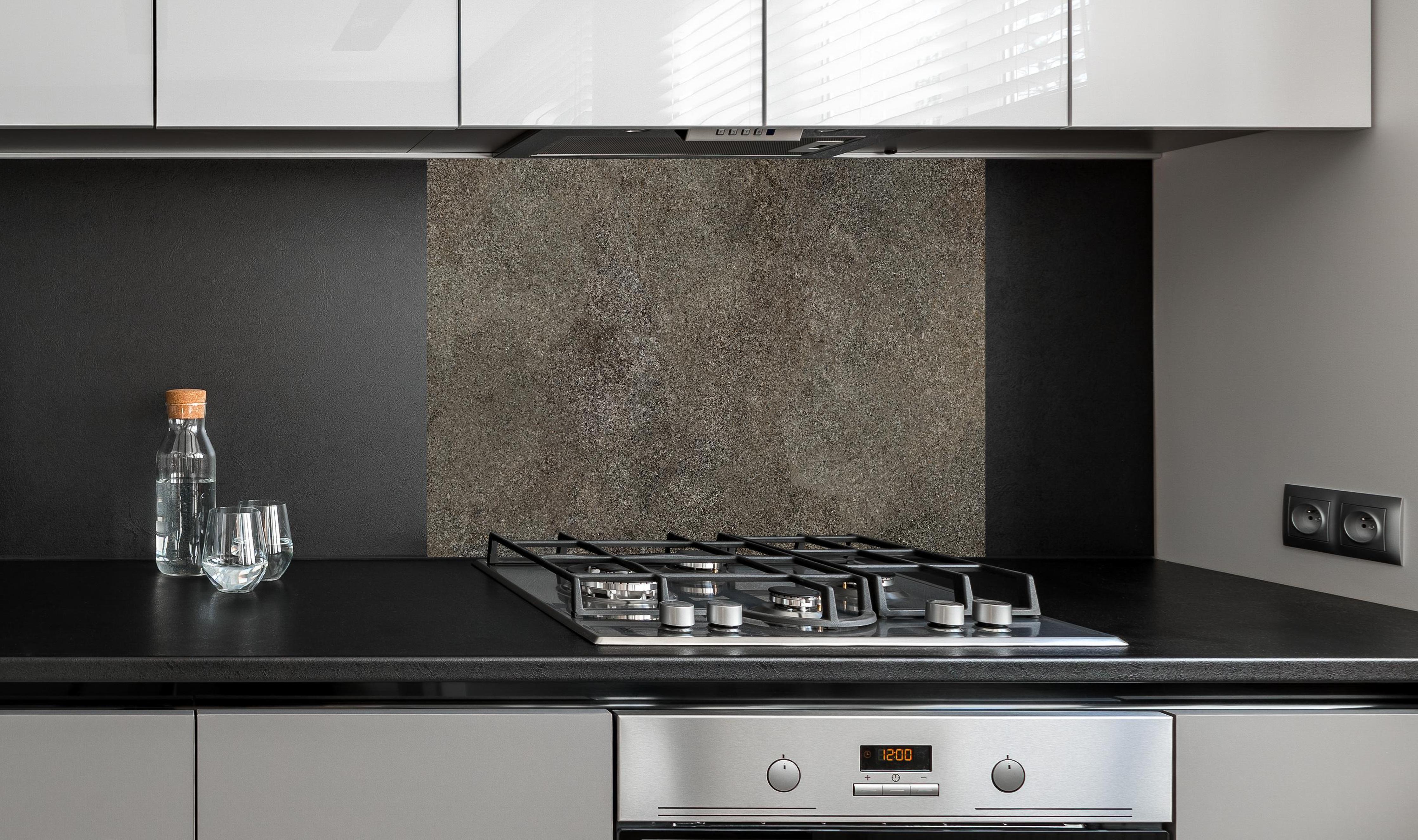 Spritzschutz - Dunkelgrauer schwarzer Schieferhintergrund hinter einem Cerankochfeld zwischen Holz-Kochutensilien