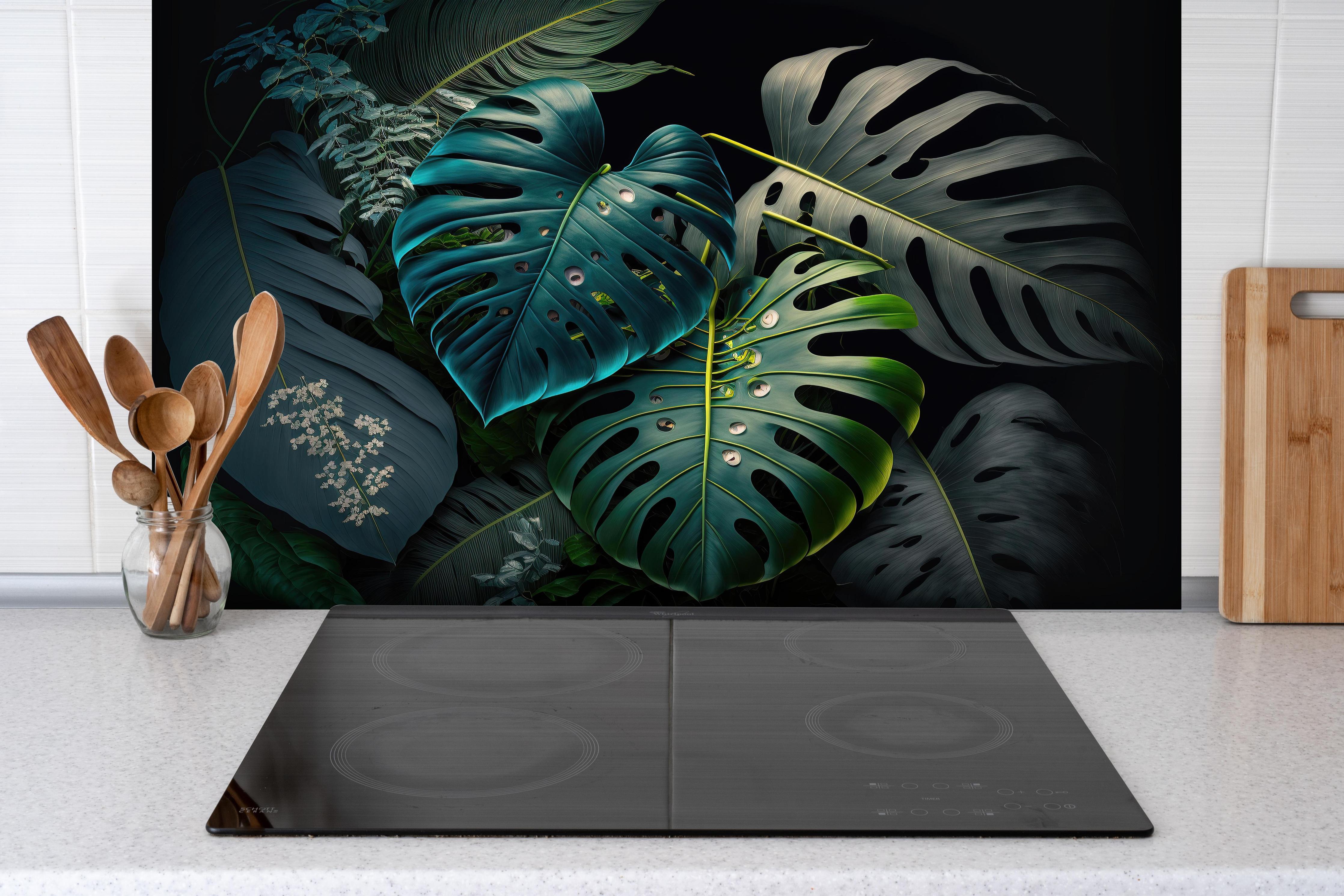 Spritzschutz - Dunkelgrüne tropische Blätter auf schwarzem Hintergrund hinter einem Cerankochfeld zwischen Holz-Kochutensilien