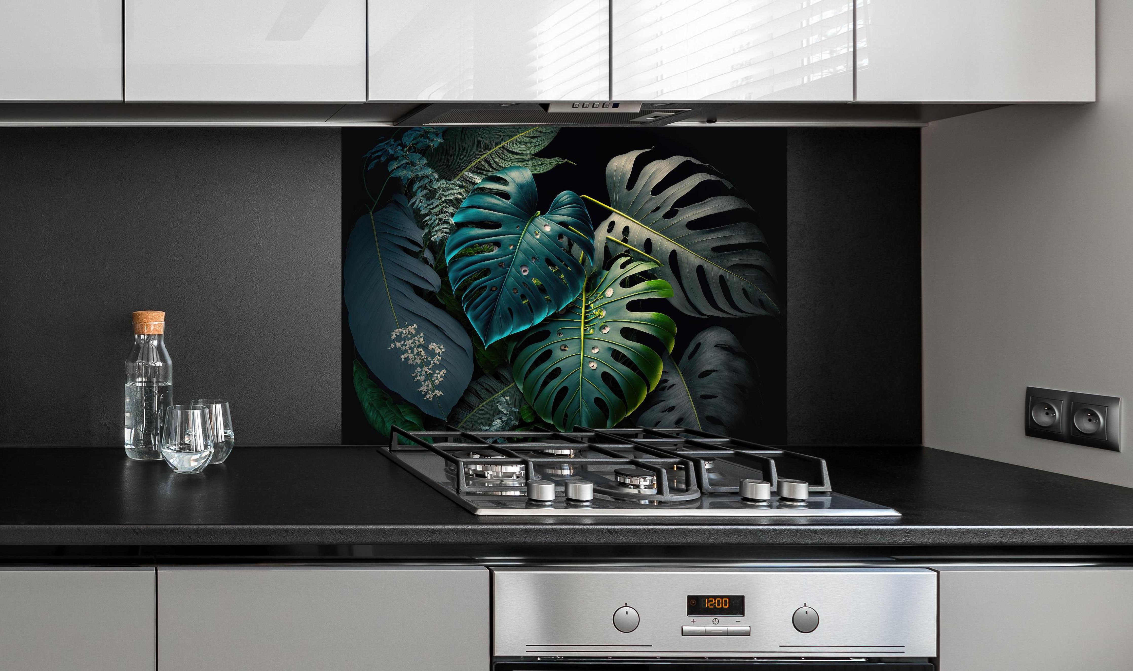Spritzschutz - Dunkelgrüne tropische Blätter auf schwarzem Hintergrund hinter einem Cerankochfeld zwischen Holz-Kochutensilien