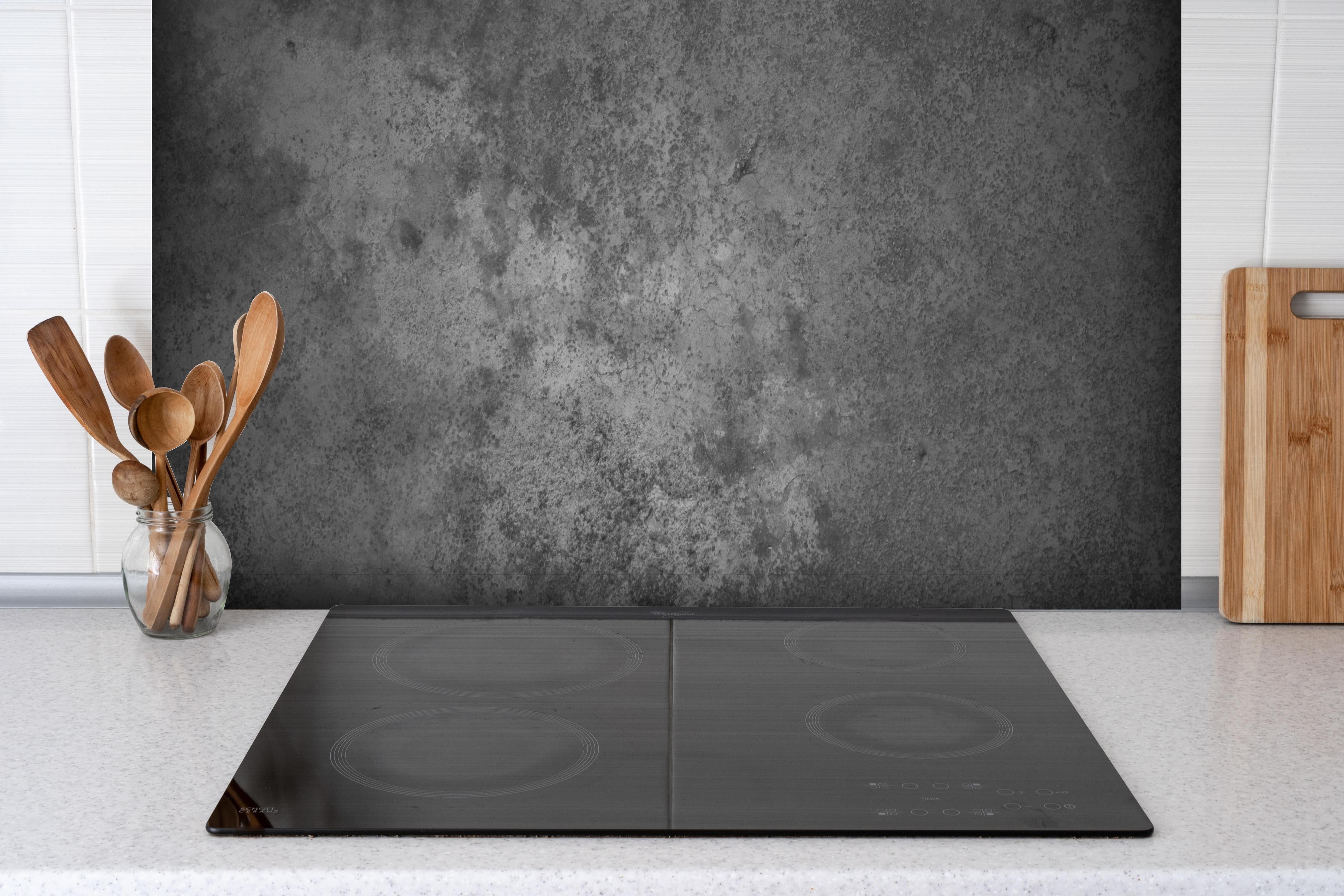 Spritzschutz - Dunkle alte Zementwand hinter einem Cerankochfeld zwischen Holz-Kochutensilien