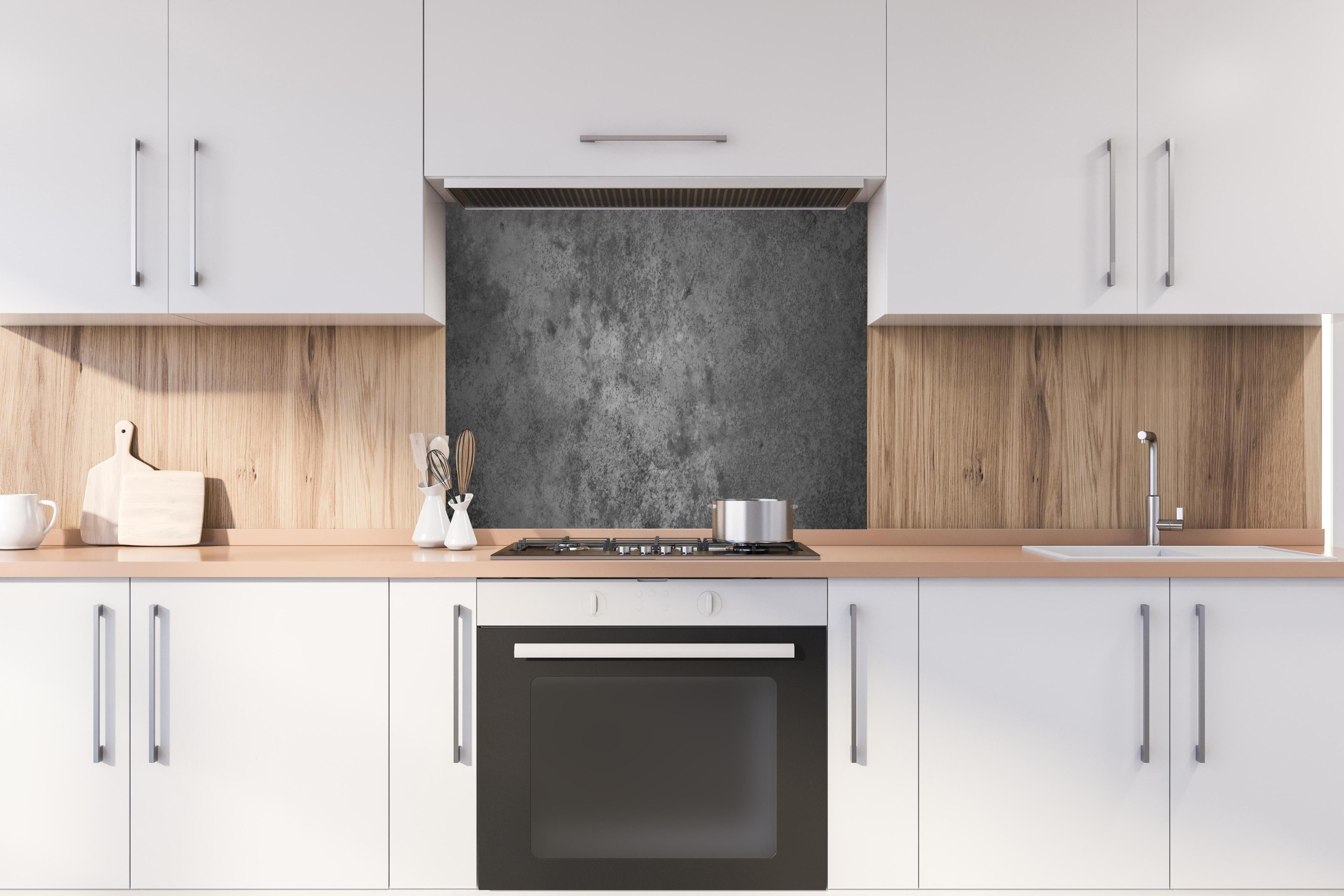 Spritzschutz - Dunkle alte Zementwand hinter einem Cerankochfeld zwischen Holz-Kochutensilien