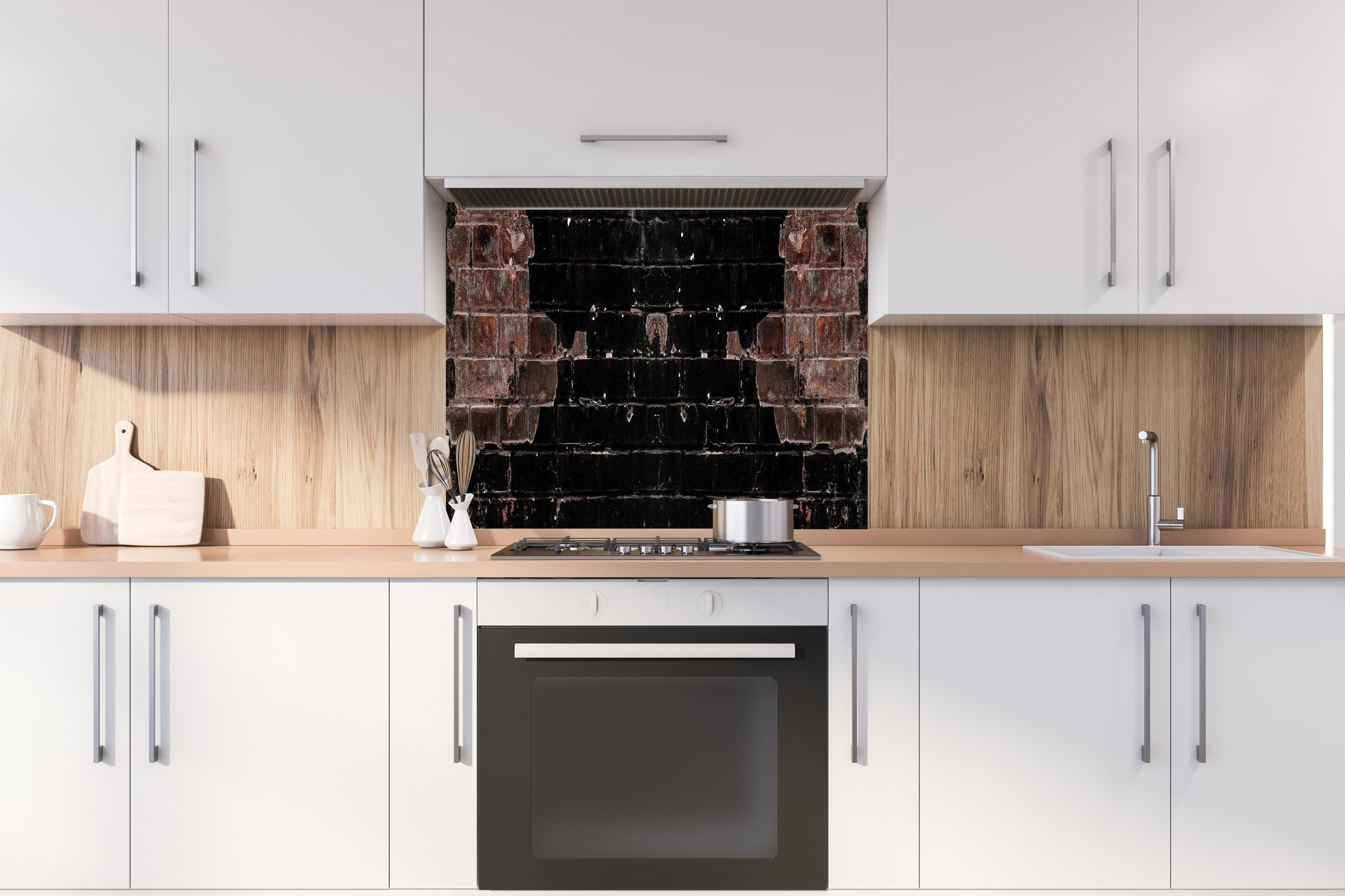 Spritzschutz - Dunkle beschädigte Ziegelwand hinter einem Cerankochfeld zwischen Holz-Kochutensilien