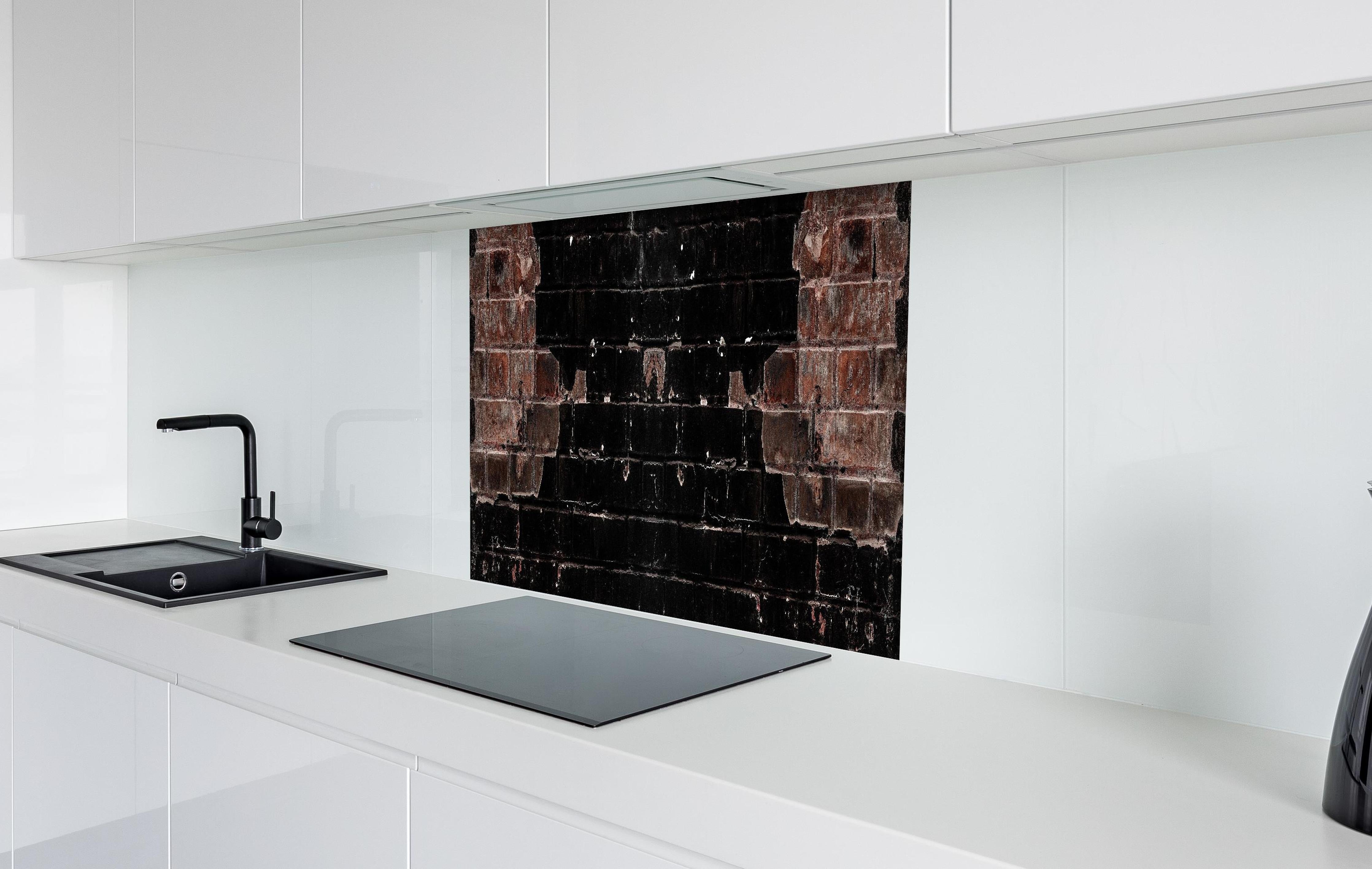 Spritzschutz - Dunkle beschädigte Ziegelwand hinter einem Cerankochfeld zwischen Holz-Kochutensilien