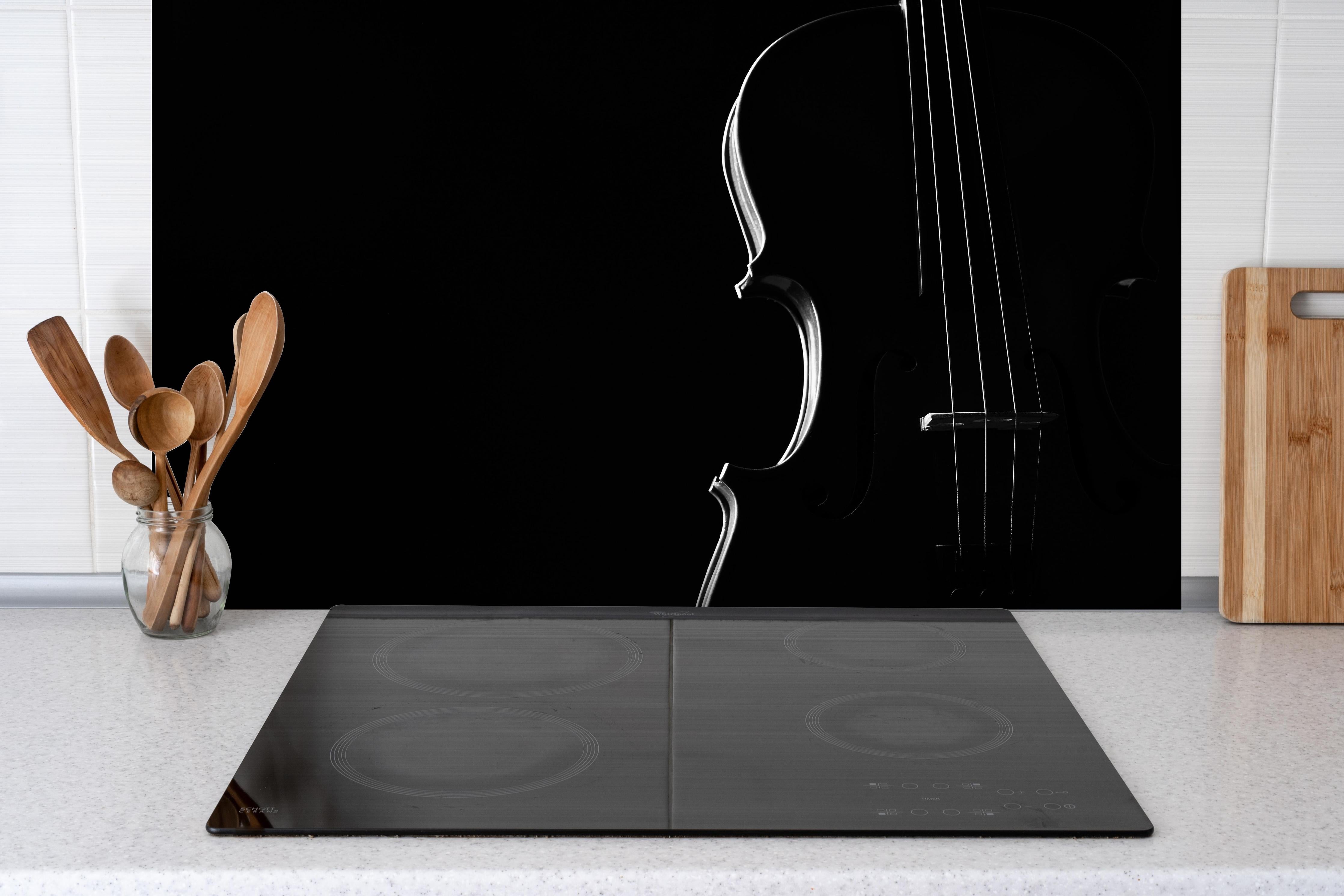 Spritzschutz - Dunkles Bild einer Violine hinter einem Cerankochfeld zwischen Holz-Kochutensilien