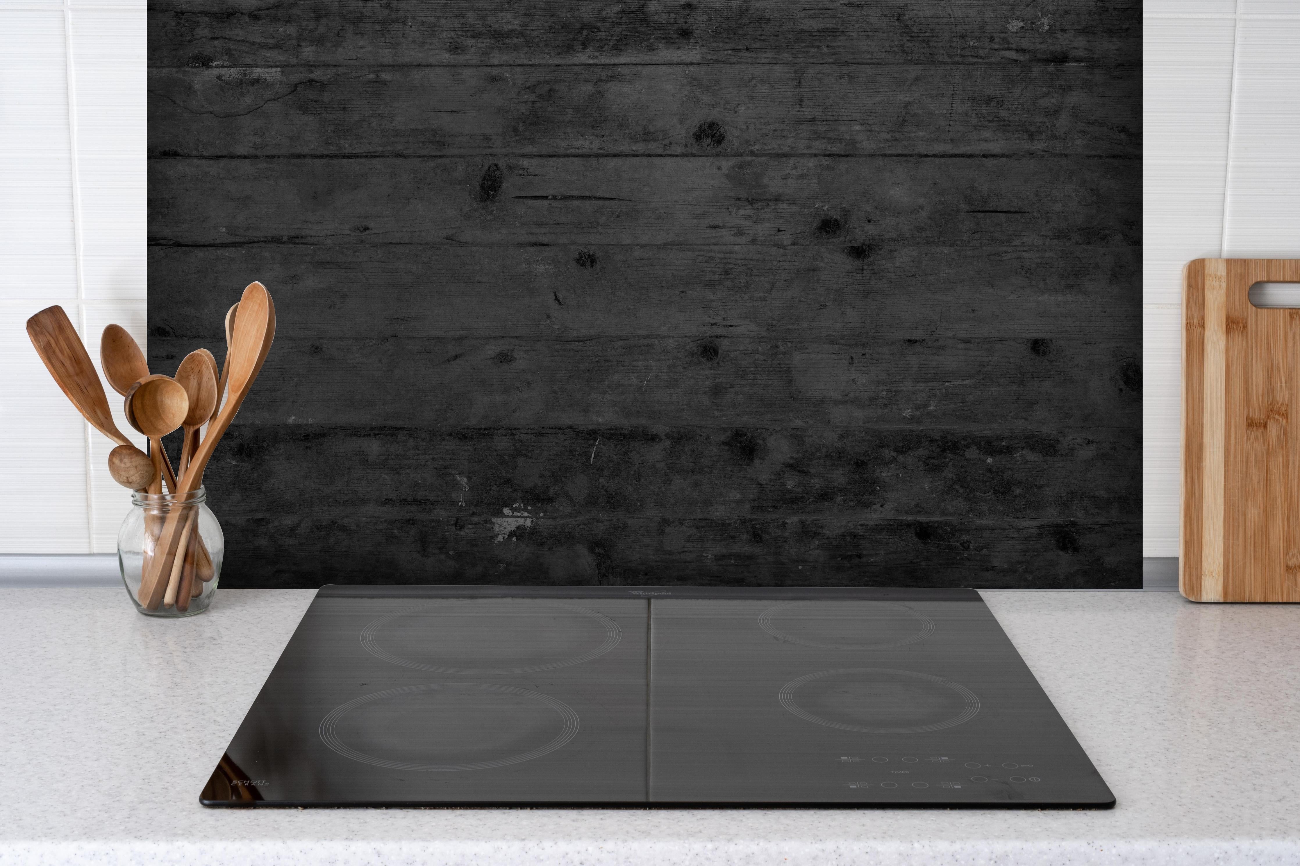 Spritzschutz - Dunkles altes Hartholz hinter einem Cerankochfeld zwischen Holz-Kochutensilien