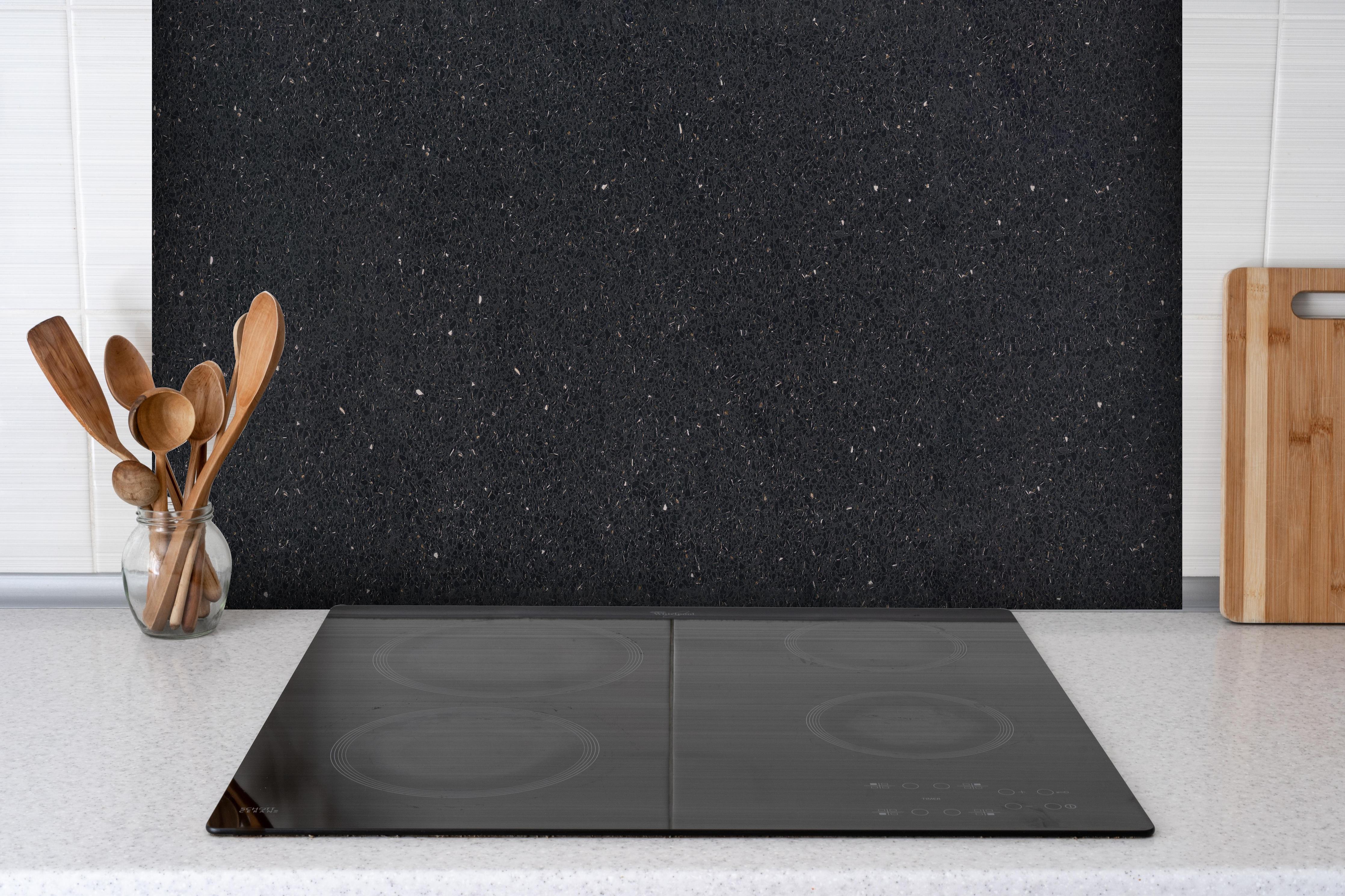 Spritzschutz - Edle schwarze Granite Marmor-Textur hinter einem Cerankochfeld zwischen Holz-Kochutensilien