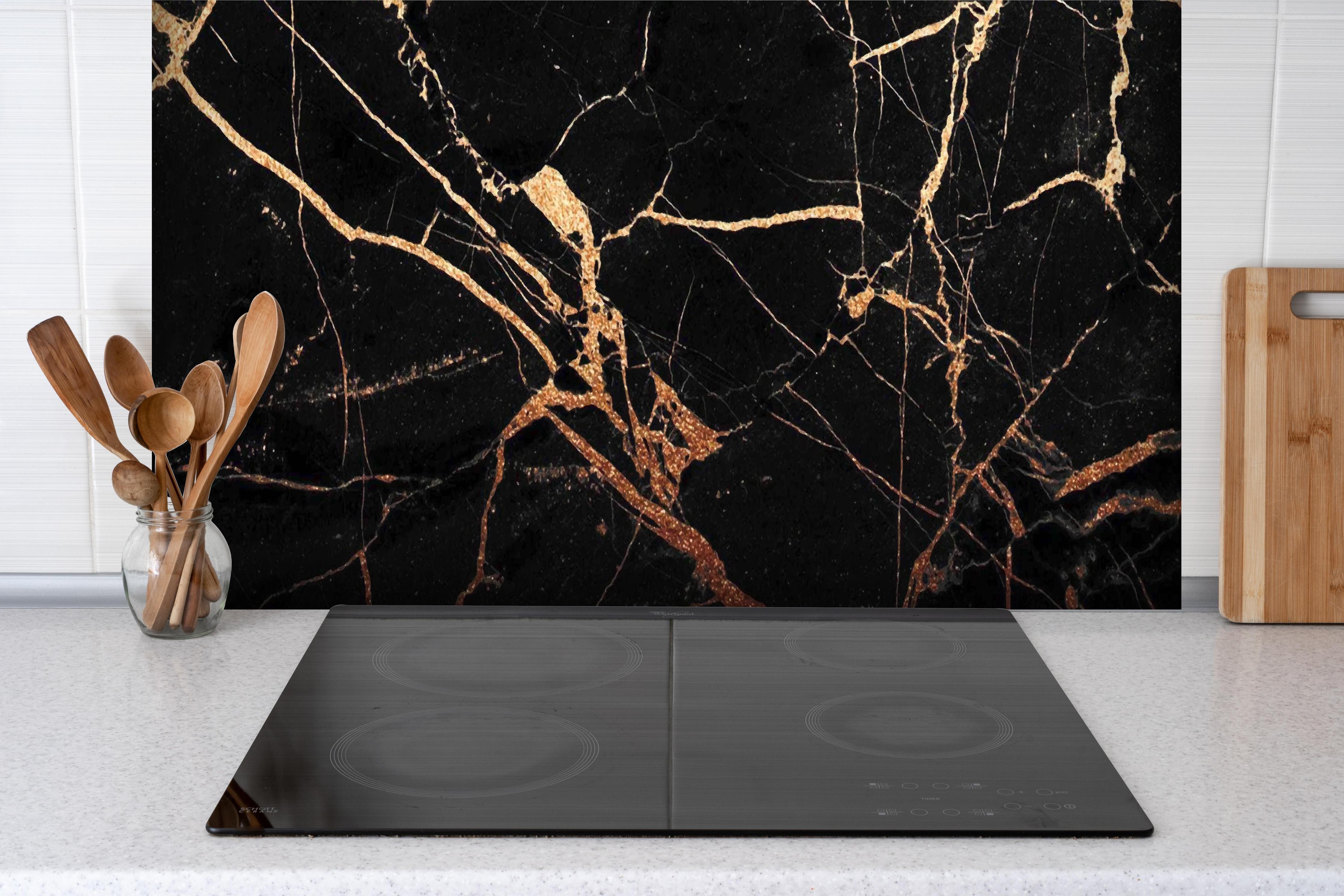 Spritzschutz - Edler Schwarz-Gold Marmor-Optik hinter einem Cerankochfeld zwischen Holz-Kochutensilien