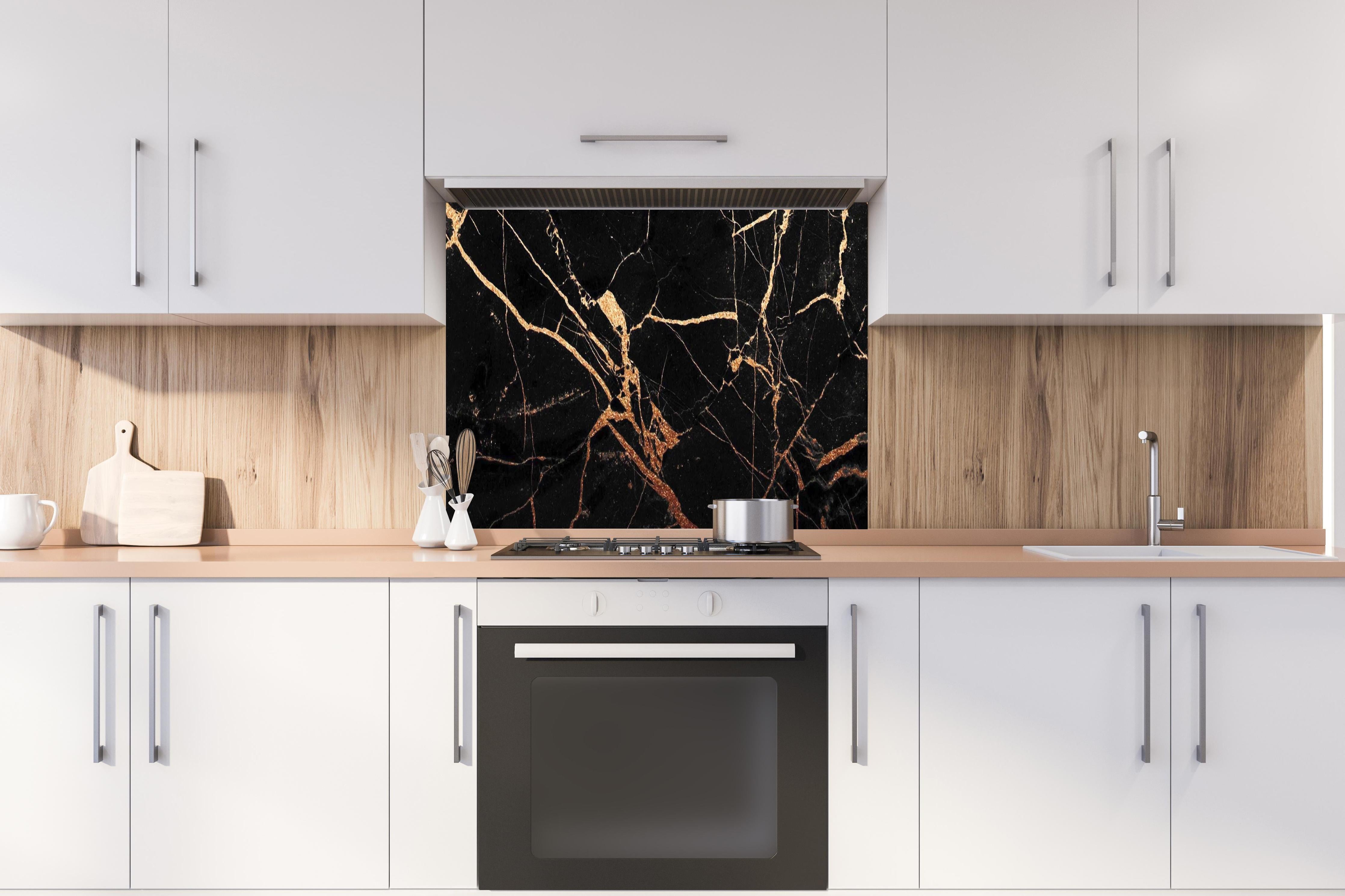 Spritzschutz - Edler Schwarz-Gold Marmor-Optik hinter einem Cerankochfeld zwischen Holz-Kochutensilien