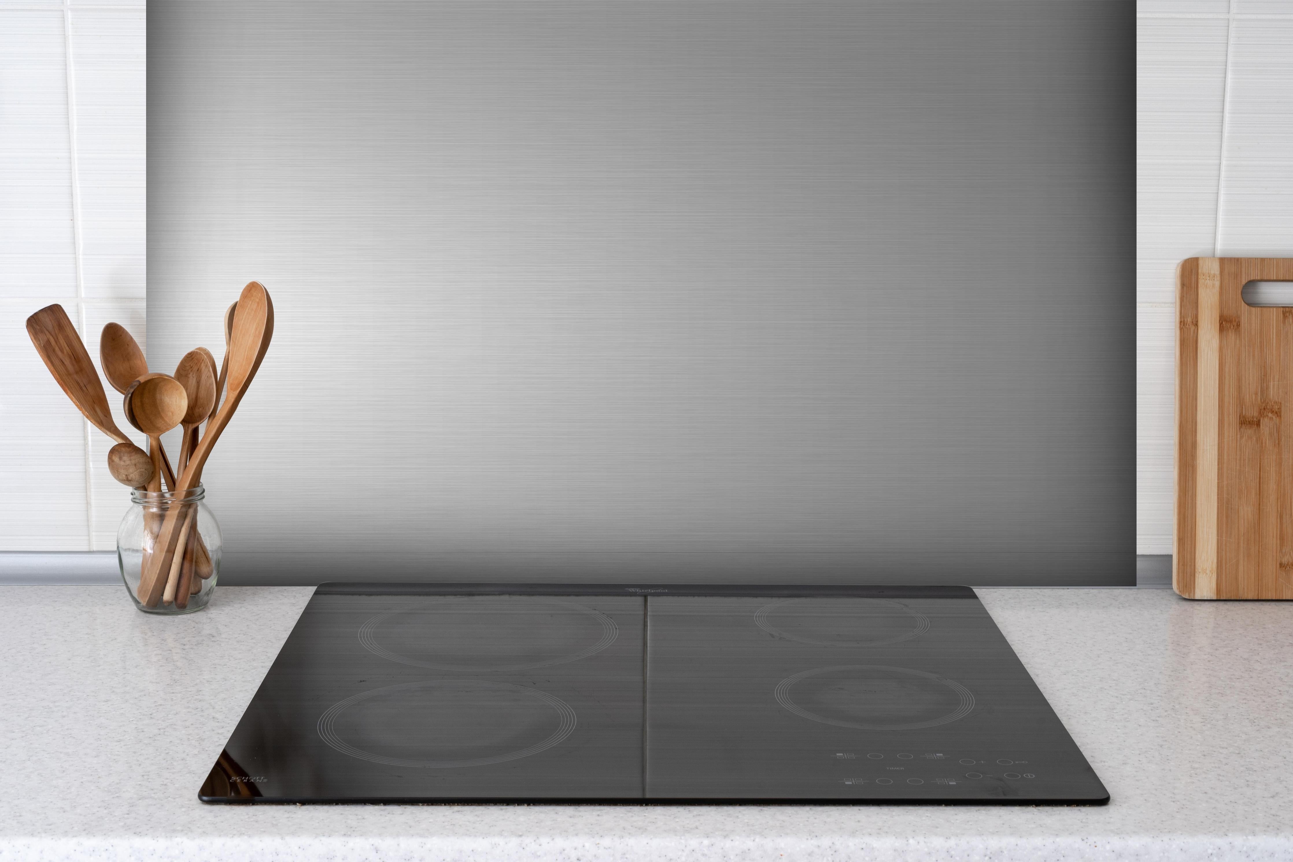 Spritzschutz - Edler gebürsteter Metall-Hintergrund in Graunuancen hinter einem Cerankochfeld zwischen Holz-Kochutensilien