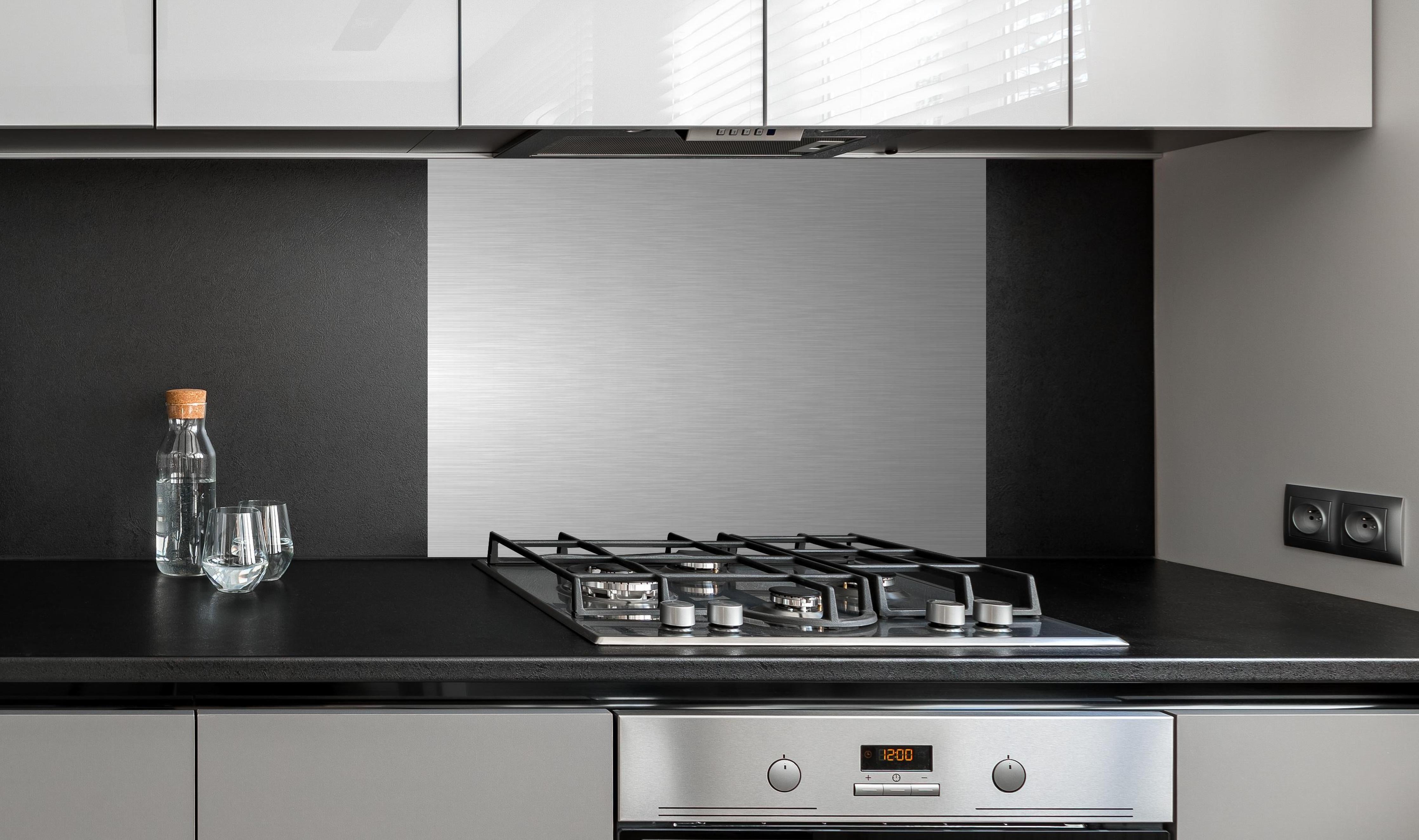 Spritzschutz - Edler gebürsteter Metall-Hintergrund in Graunuancen hinter einem Cerankochfeld zwischen Holz-Kochutensilien