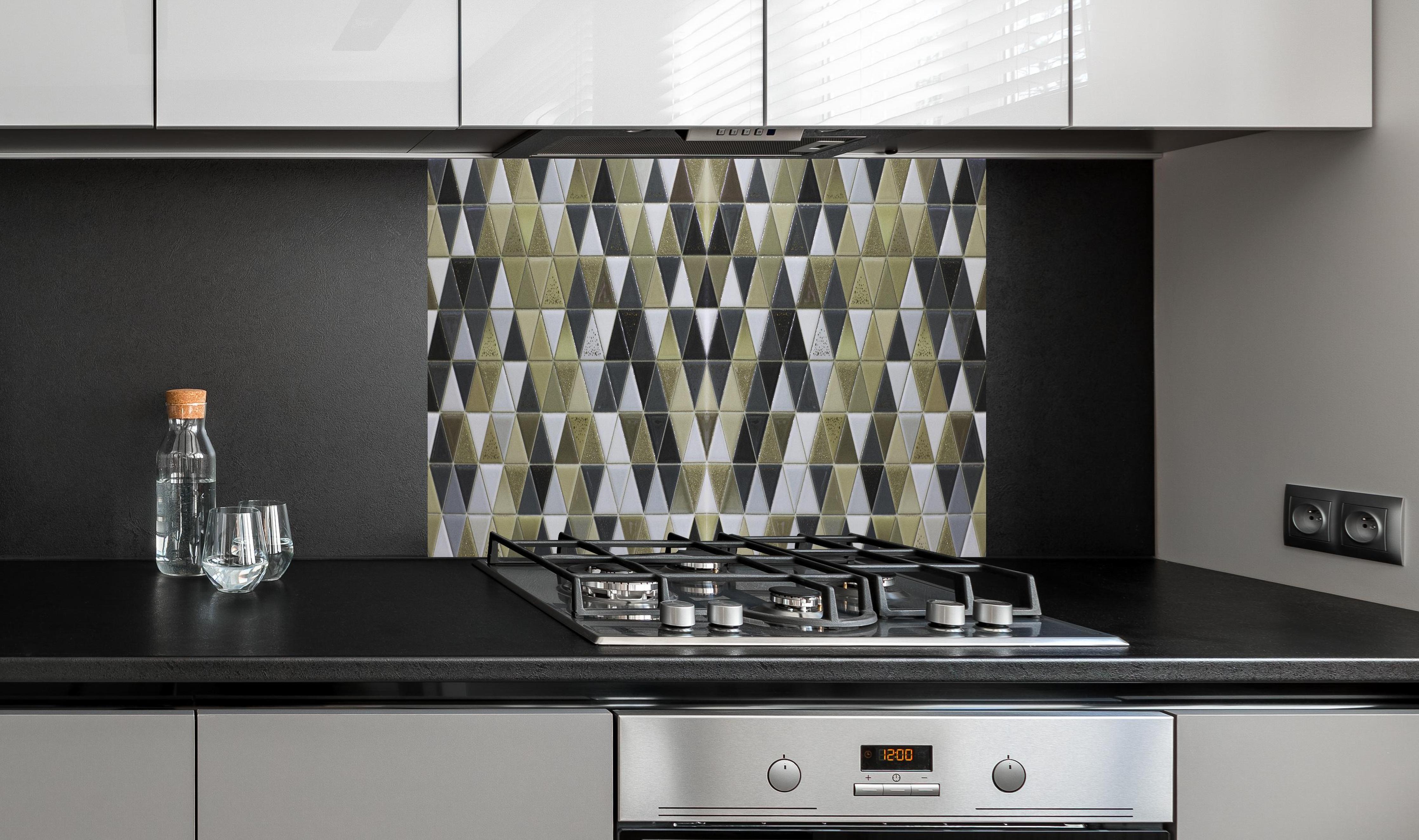 Spritzschutz - Edles Fliesen-Dekor in Schwarz, Weiß und Gold hinter einem Cerankochfeld zwischen Holz-Kochutensilien