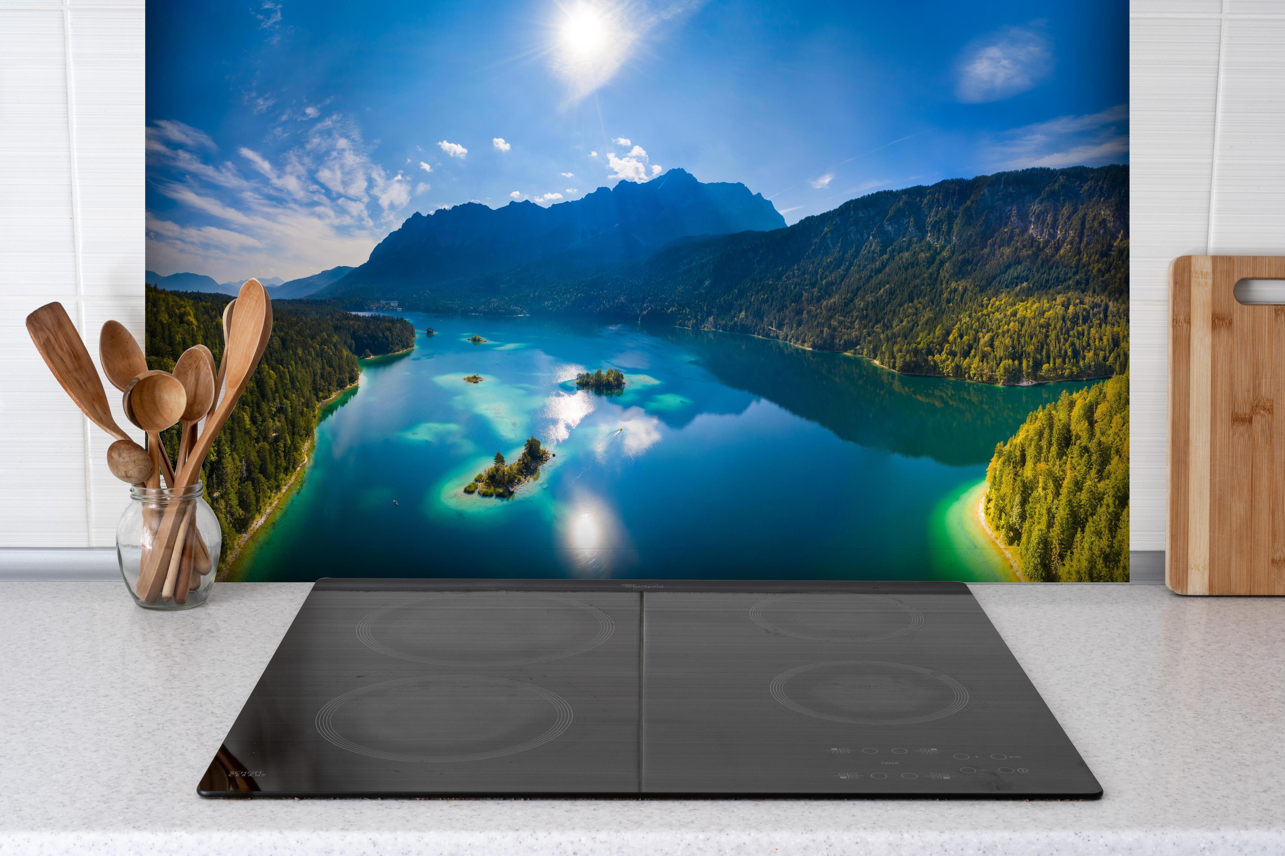 Spritzschutz - Eibsees mit der Zugspitze im Hintergrund hinter einem Cerankochfeld zwischen Holz-Kochutensilien