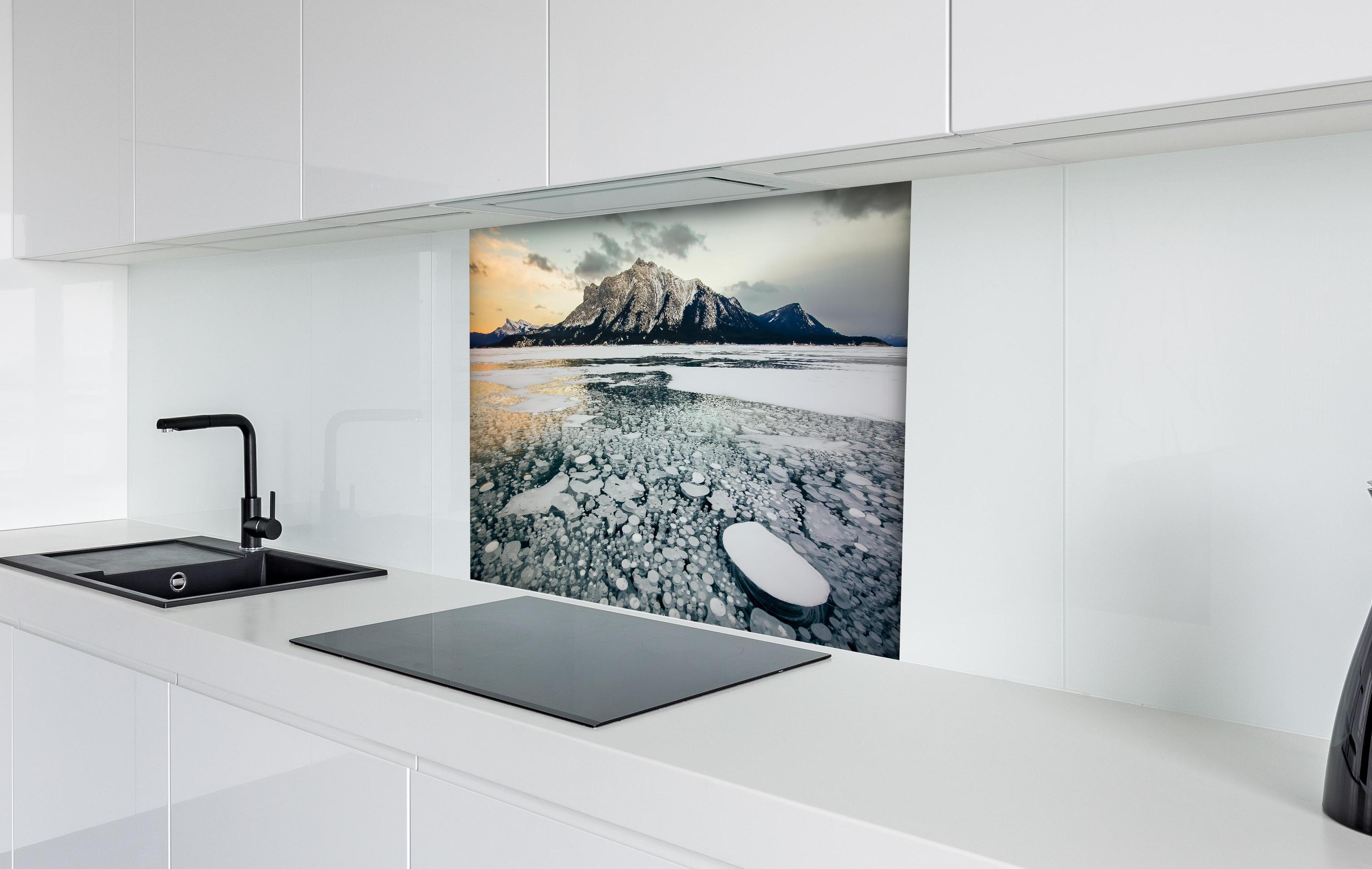 Spritzschutz - Eisblasen im gefrorenen Bergsee bei Sonnenuntergang hinter einem Cerankochfeld zwischen Holz-Kochutensilien