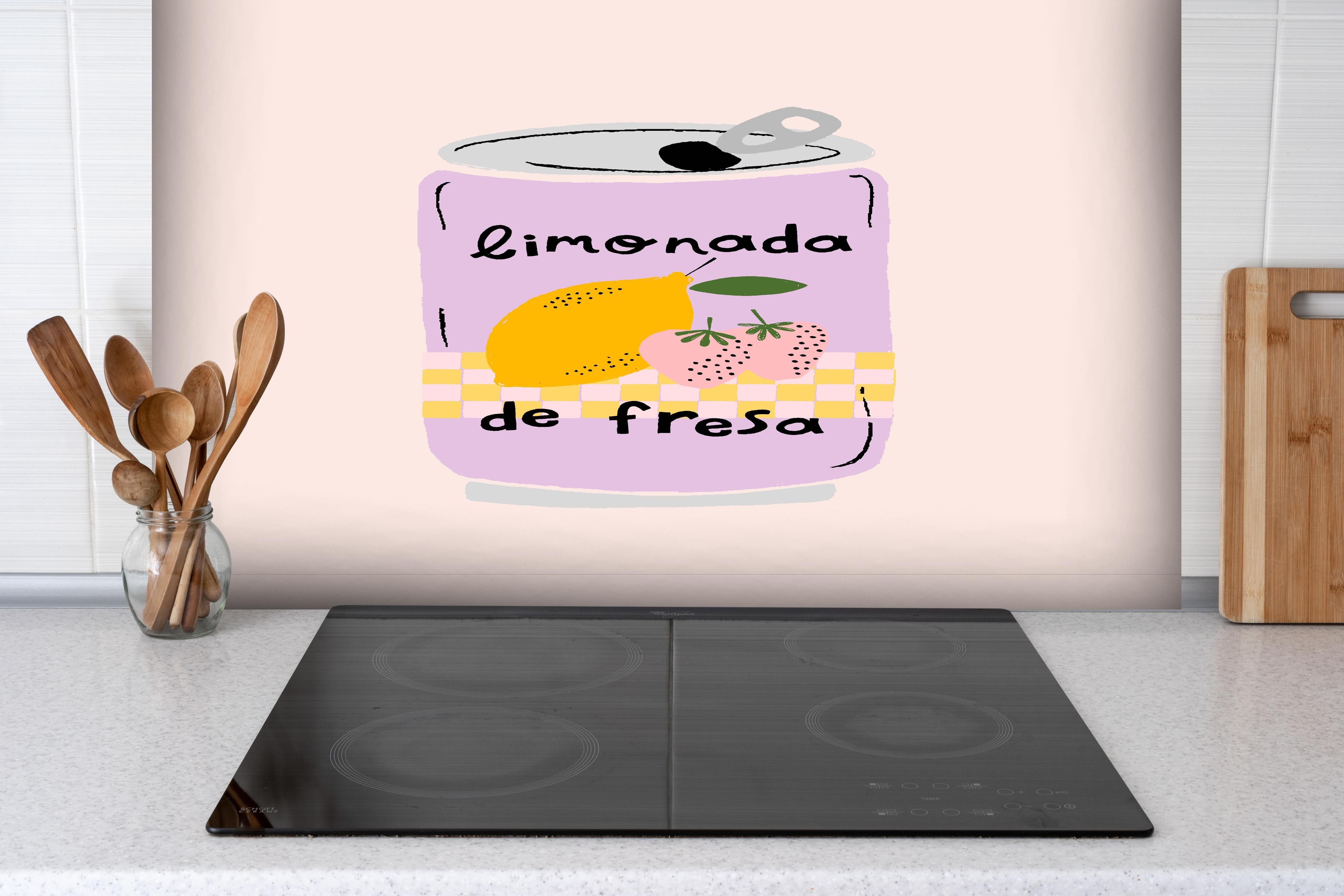 Spritzschutz - Eistee Dose mit Zitrusfrucht & Erdbeeren hinter einem Cerankochfeld zwischen Holz-Kochutensilien