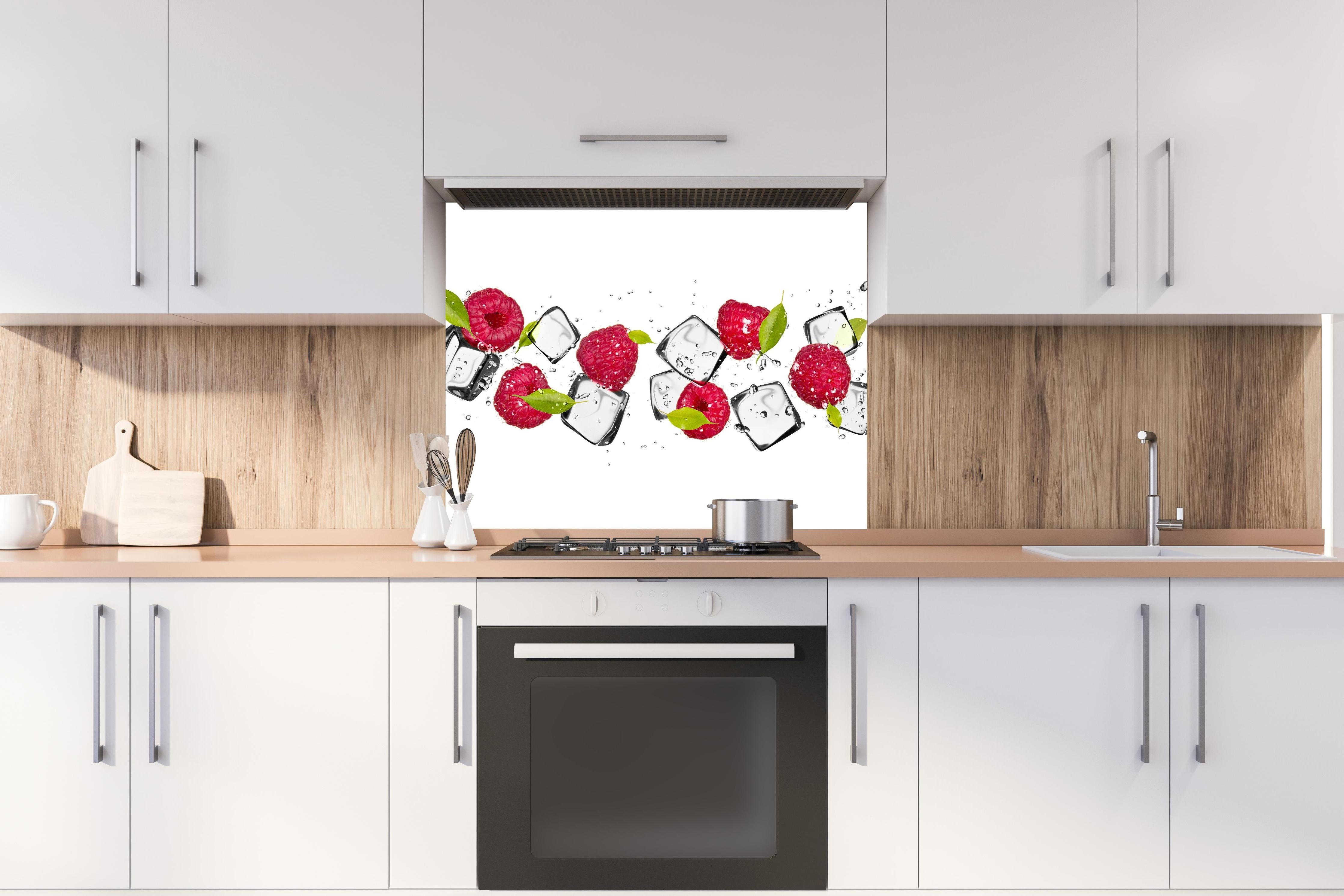 Spritzschutz - Eiswürfel mit Himbeeren hinter einem Cerankochfeld zwischen Holz-Kochutensilien