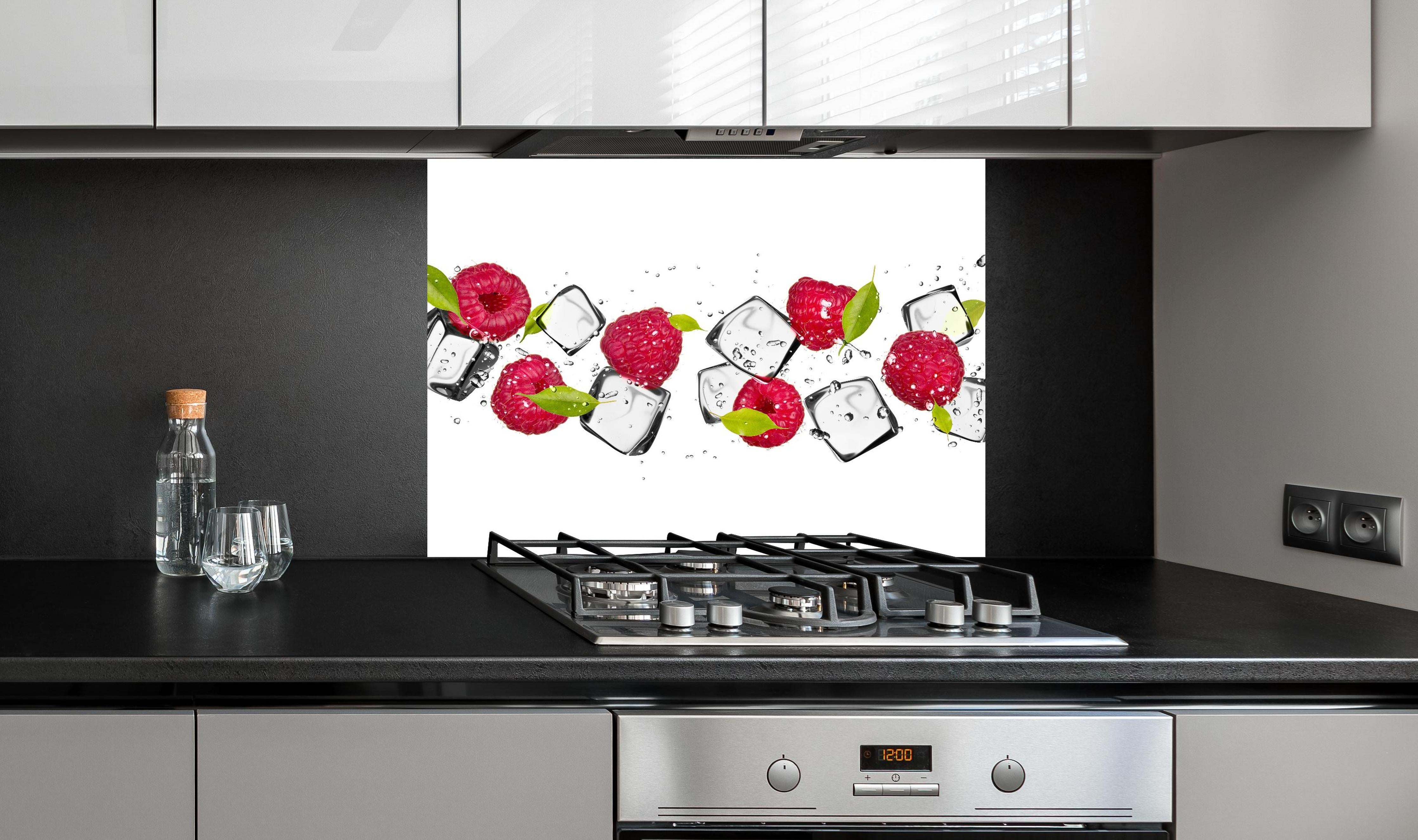 Spritzschutz - Eiswürfel mit Himbeeren hinter einem Cerankochfeld zwischen Holz-Kochutensilien