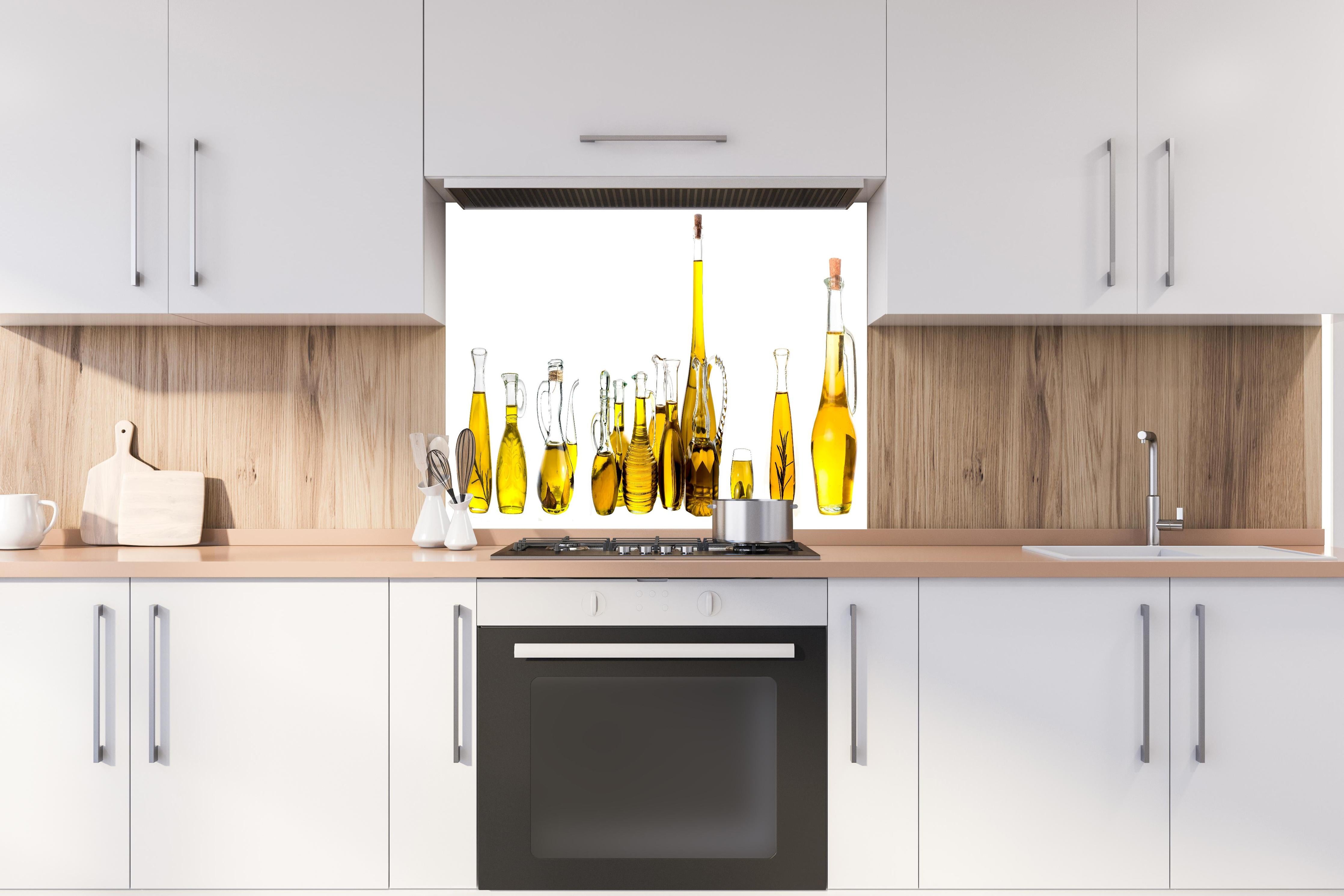Spritzschutz - Elegante Auswahl Gelber Olivenölflaschen hinter einem Cerankochfeld zwischen Holz-Kochutensilien