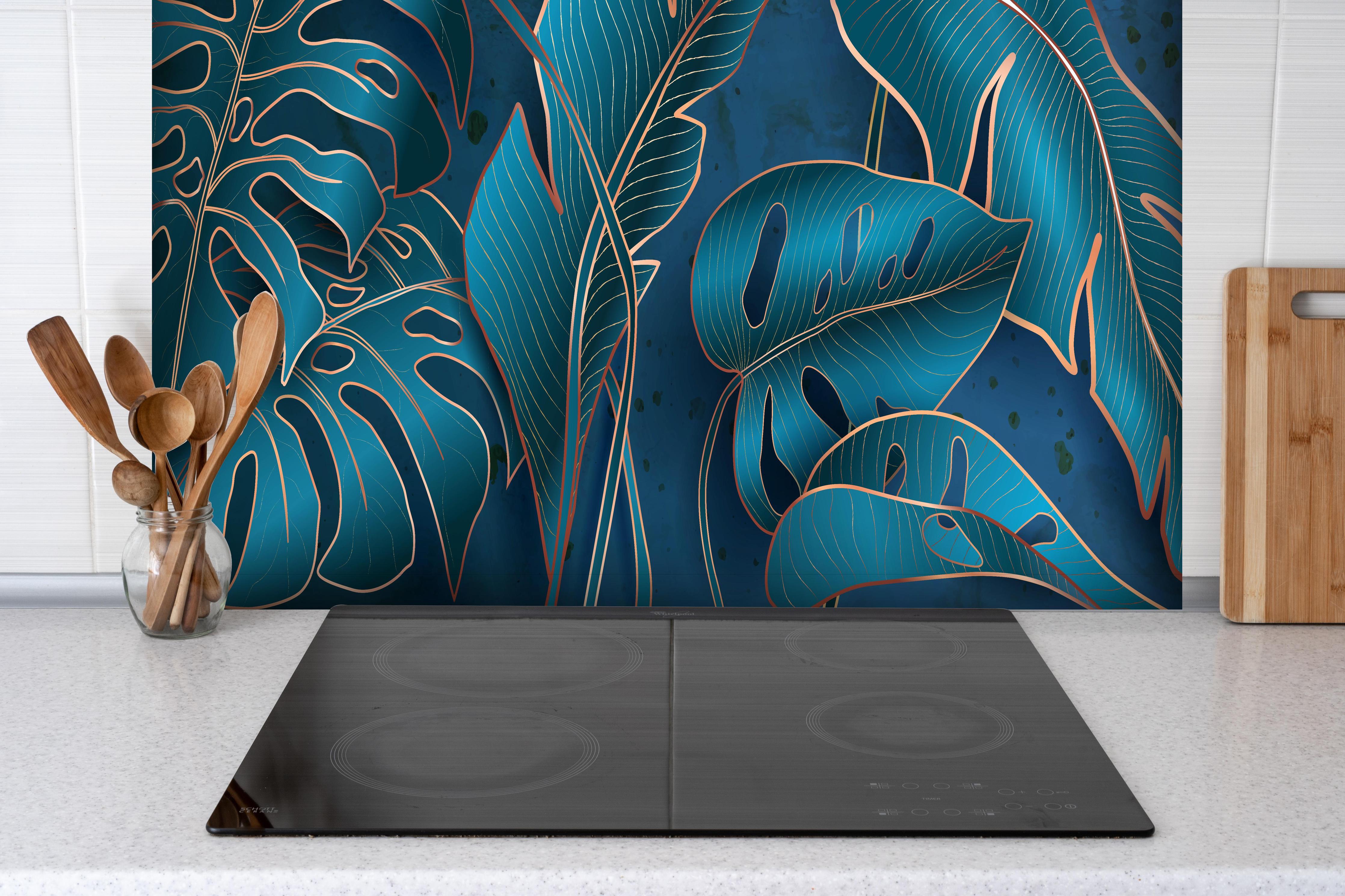 Spritzschutz - Elegante Blätter in Blau und Metallic-Tönen hinter einem Cerankochfeld zwischen Holz-Kochutensilien