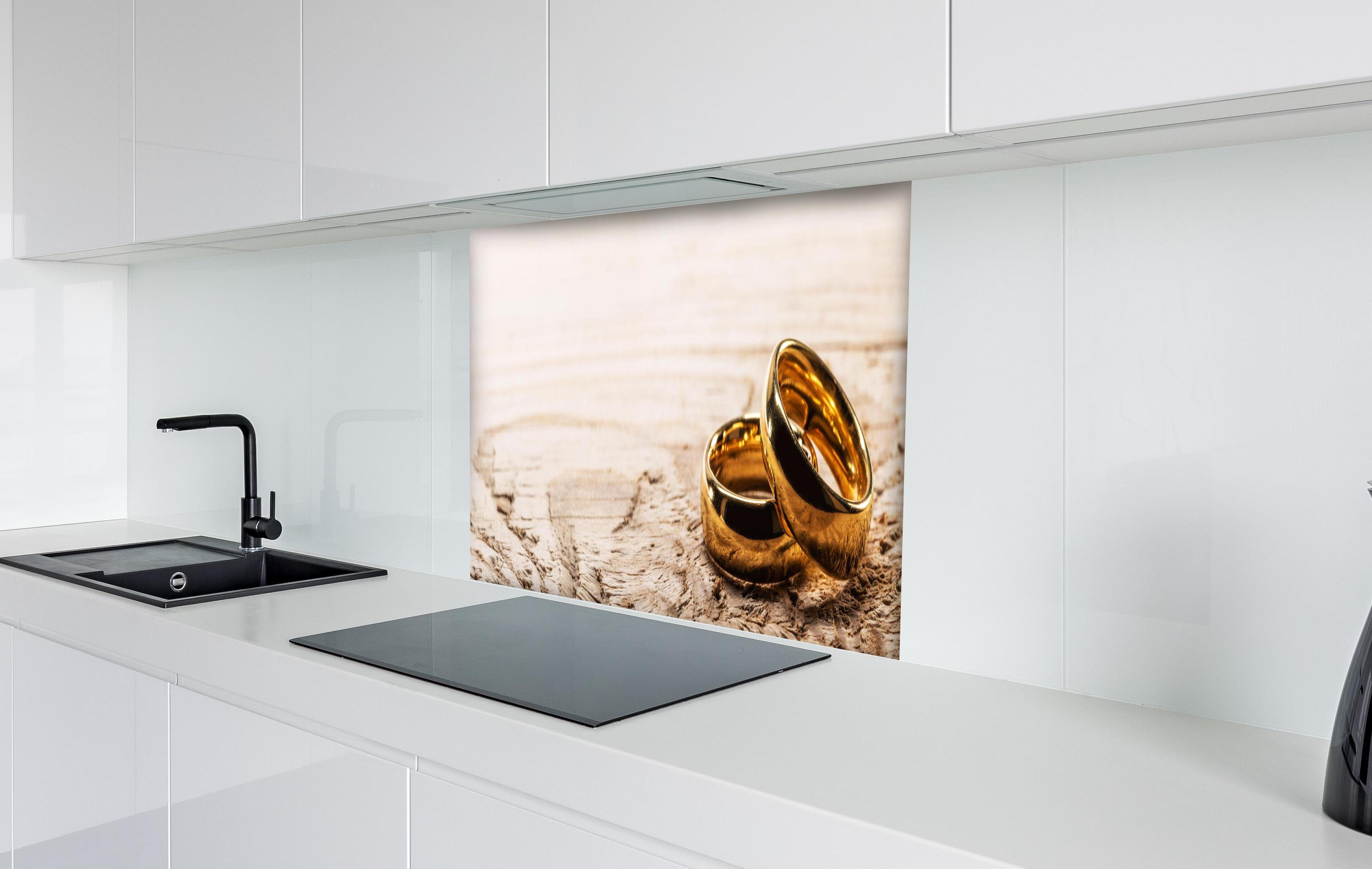 Spritzschutz - Elegante Goldringe auf rustikalem Holz hinter einem Cerankochfeld zwischen Holz-Kochutensilien