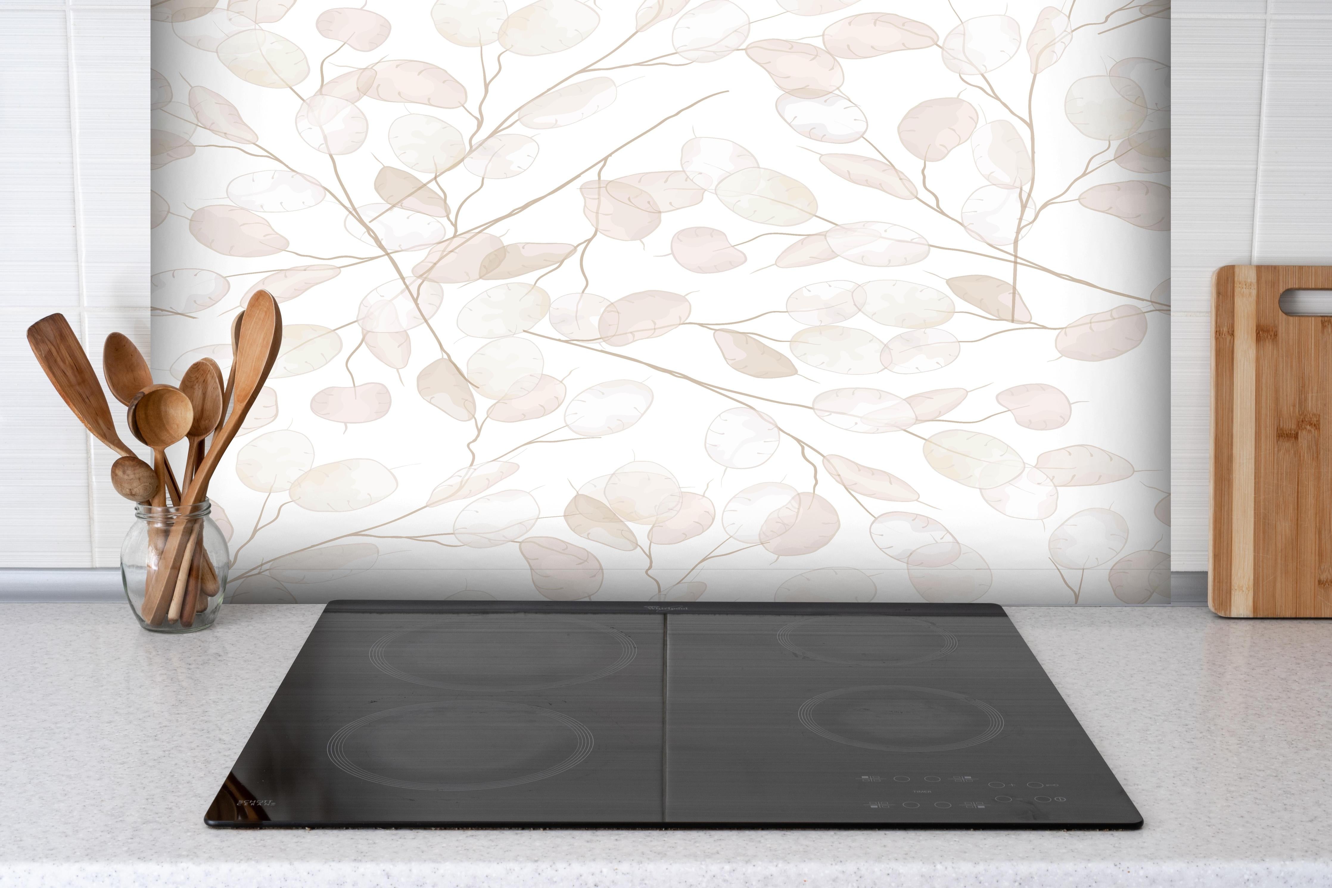 Spritzschutz - Elegante weiße Blätter mit Grauakzenten hinter einem Cerankochfeld zwischen Holz-Kochutensilien