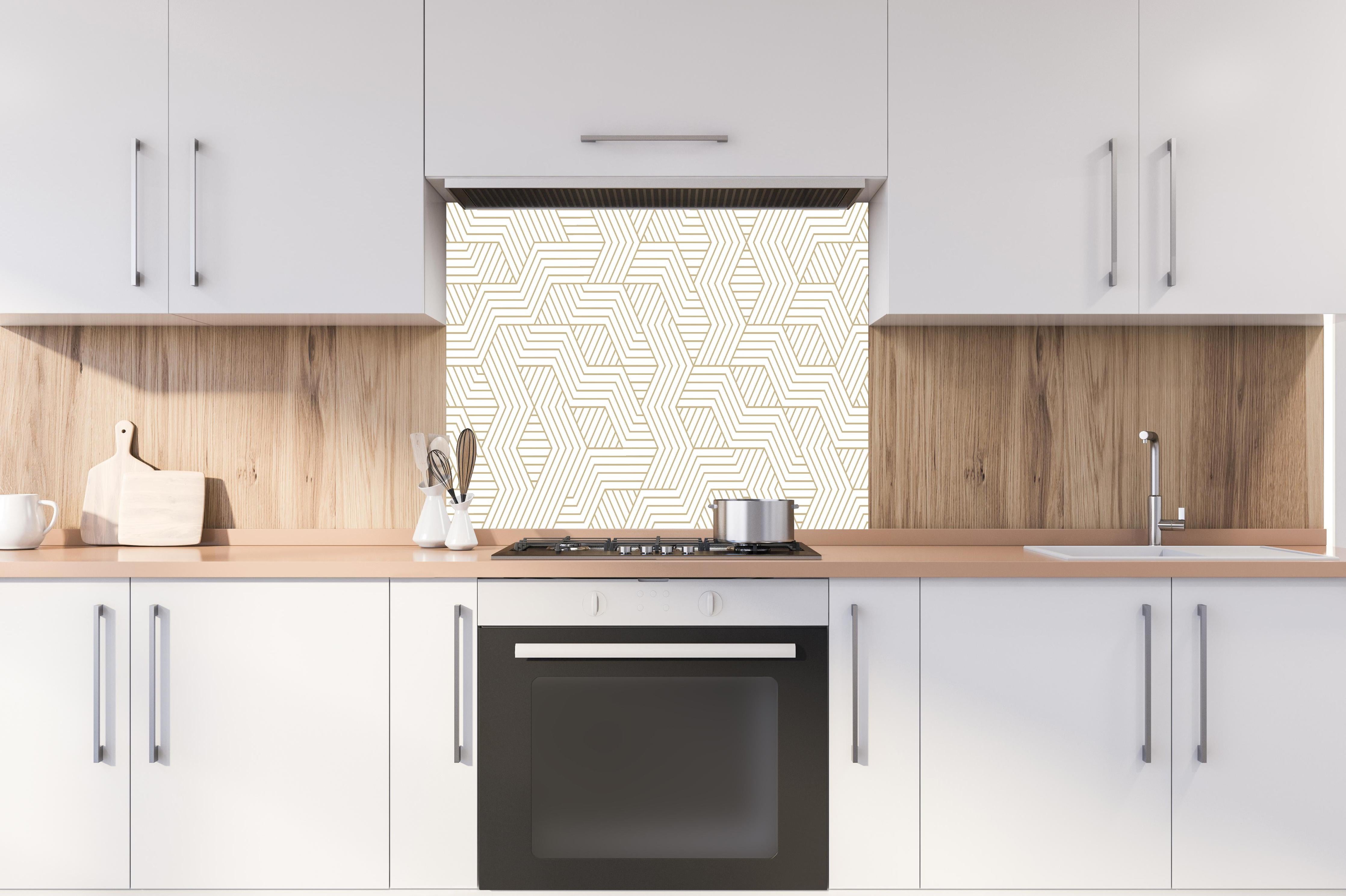 Spritzschutz - Eleganter Hintergrund mit geometrischem Gold und Weiß hinter einem Cerankochfeld zwischen Holz-Kochutensilien