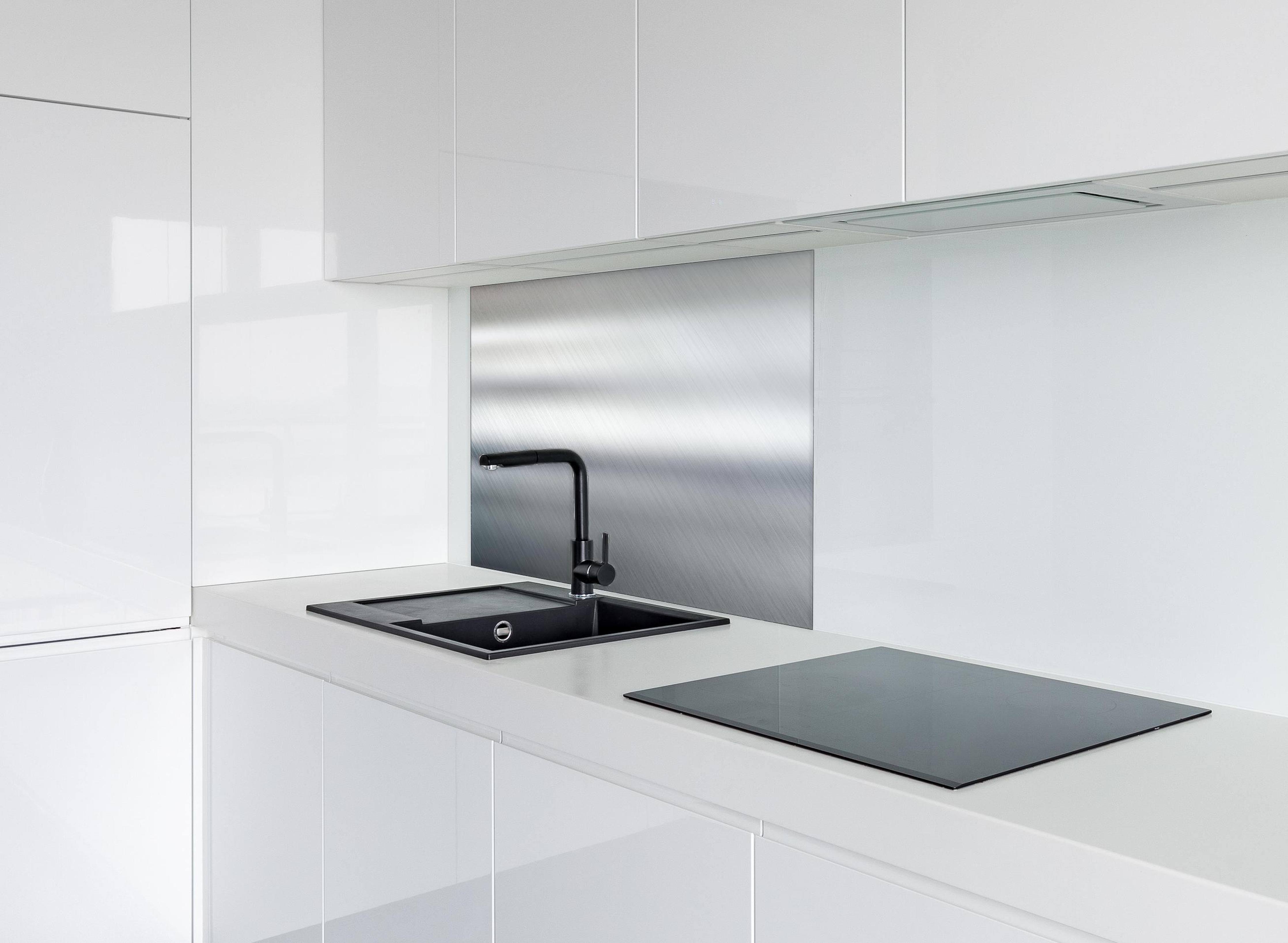 Spritzschutz - Eleganter gebürsteter Metall Hintergrund hinter einem Cerankochfeld zwischen Holz-Kochutensilien