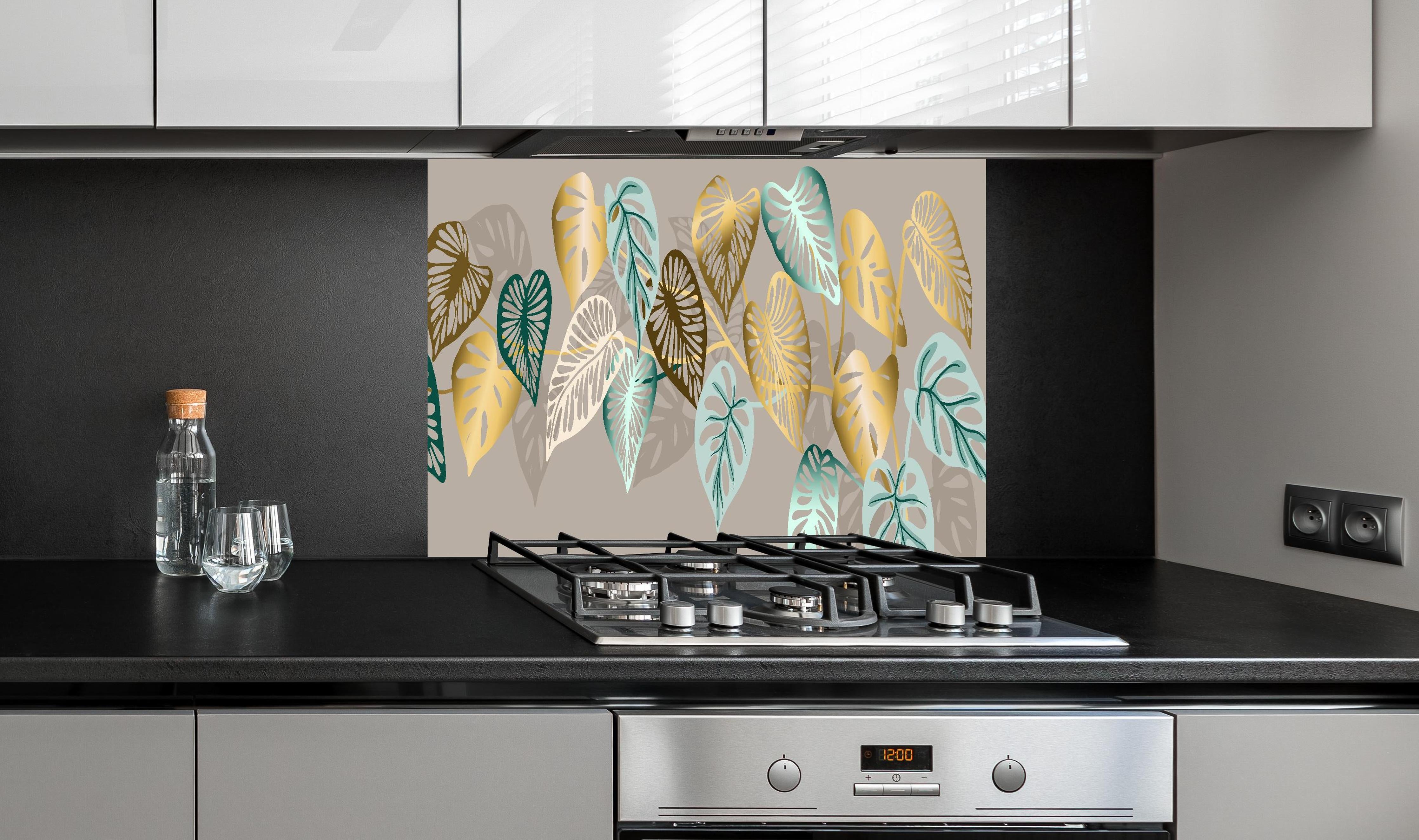 Spritzschutz - Elegantes Blattmuster in Goldtönen hinter einem Cerankochfeld zwischen Holz-Kochutensilien